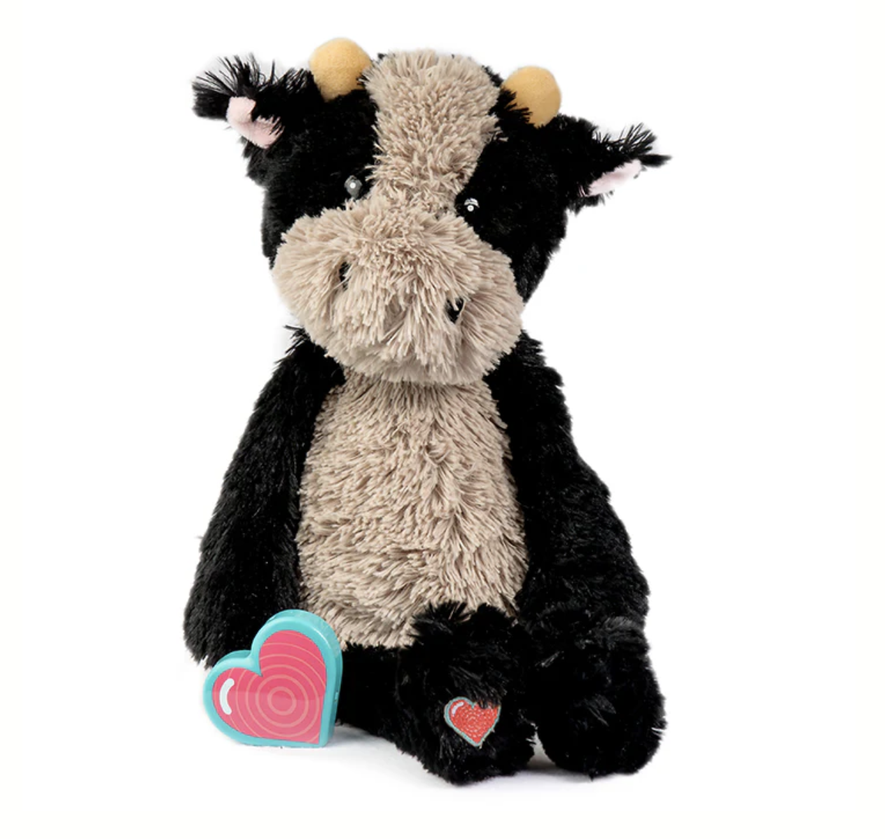A plush gray elephant stuffed toy with large floppy ears, sitting on a white background with a pink and blue heart-shaped object next to it and a small red heart on its foot.