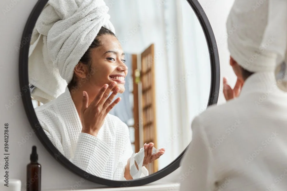 Black_woman_in_mirror_applying_face_moisturizer