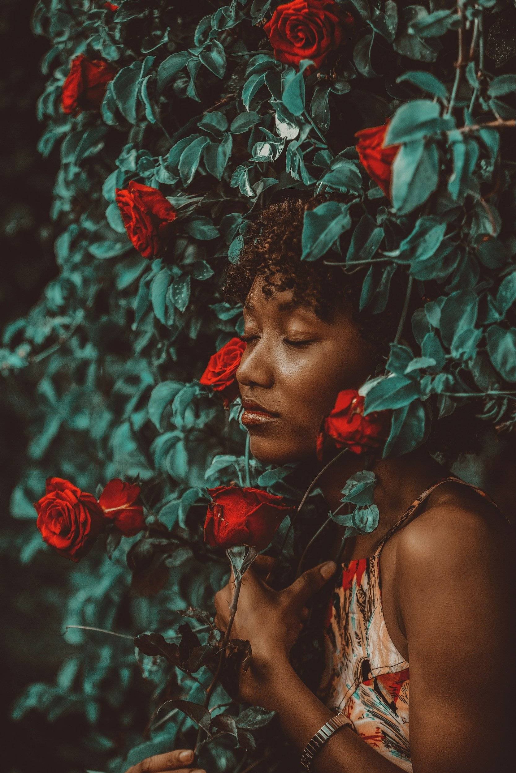 woman surrounded by red flowers