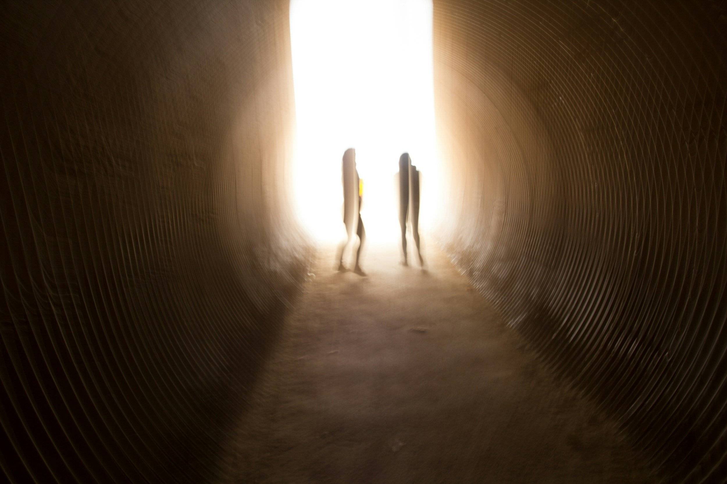 People standing in a tunnel with a light at the end
