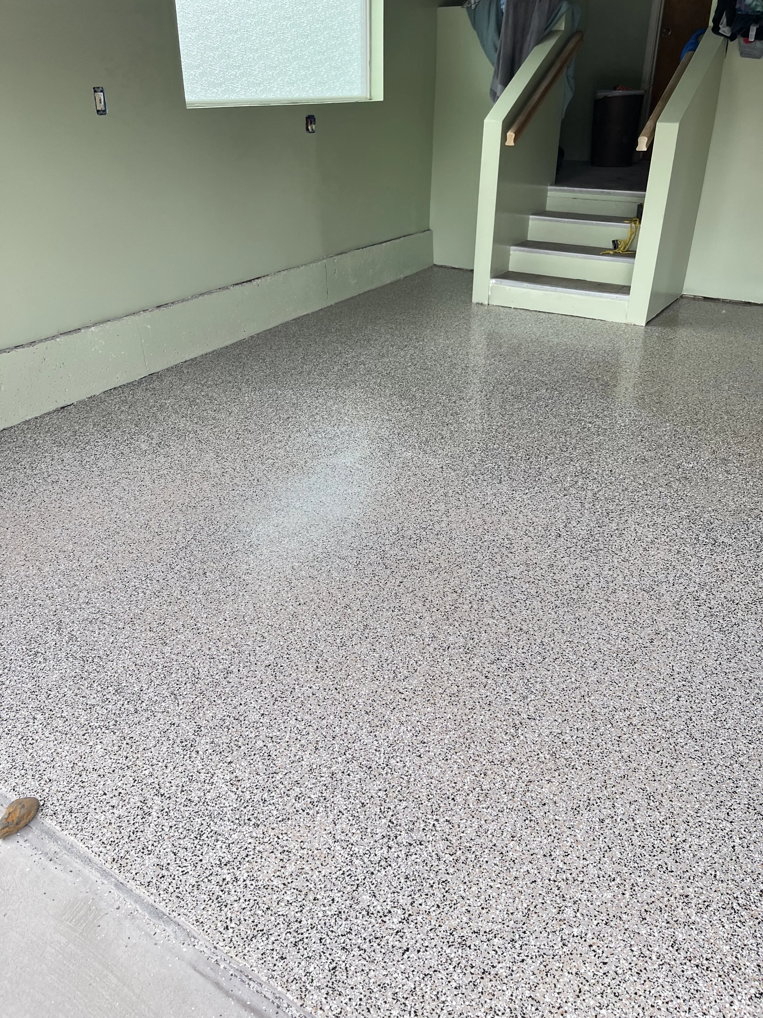 Clean speckled epoxy flooring in an indoor space with a staircase leading to an upper level.