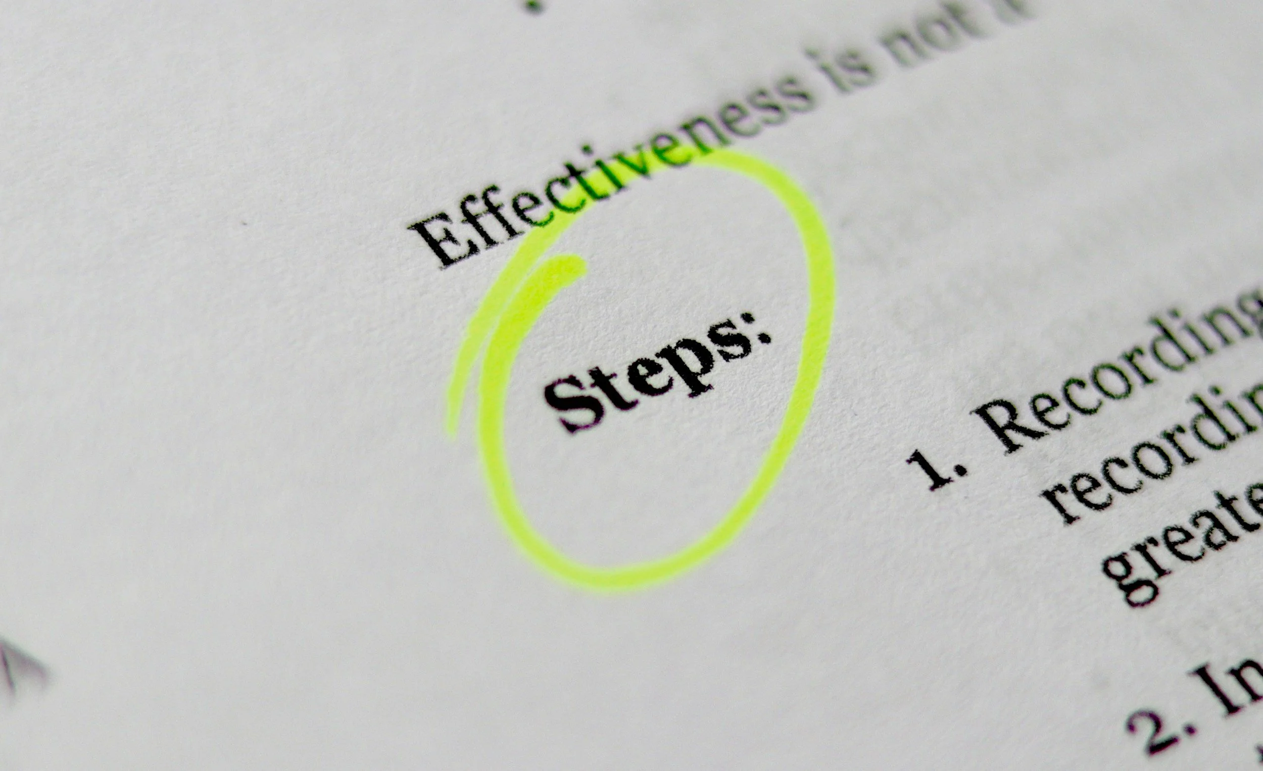 Close-up photograph of a printed document highlighting the word 'Steps:' with a neon yellow circle around it.