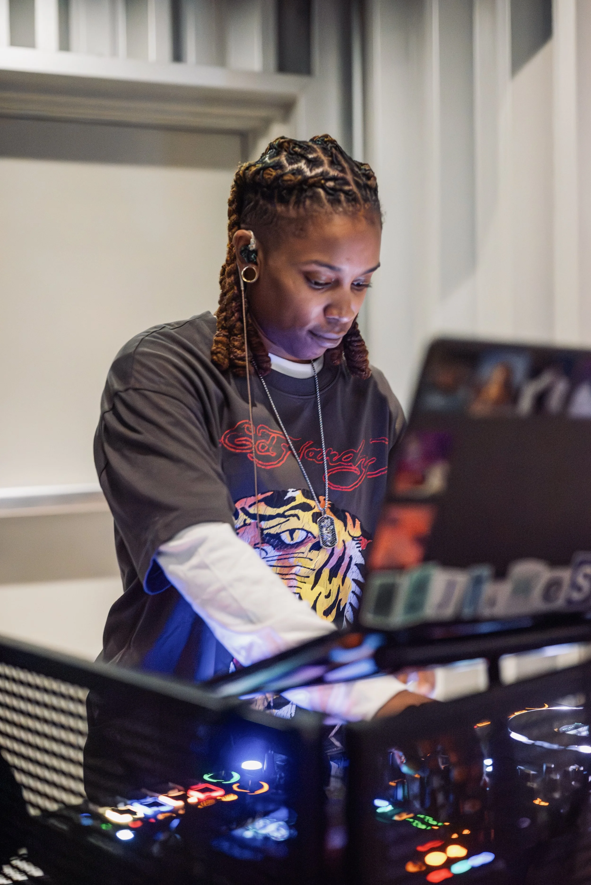 DJ focused at their setup, lit by soft blue and white light, wearing an Ed Hardy shirt and headphones, capturing the calm, creative energy of Shy Rockstar Studios.