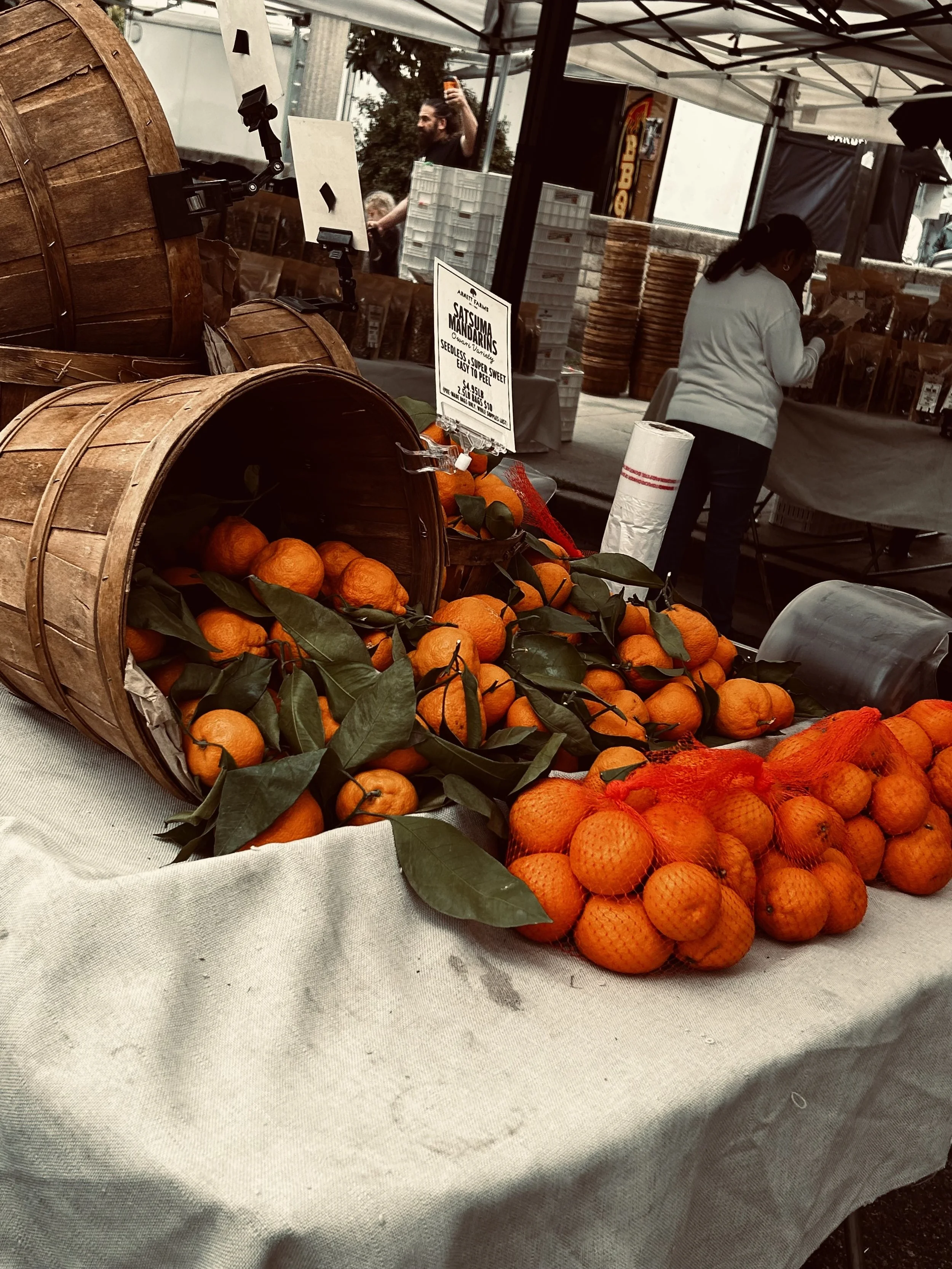 Fresh mandarins spilling from wooden baskets at a local farmers market.