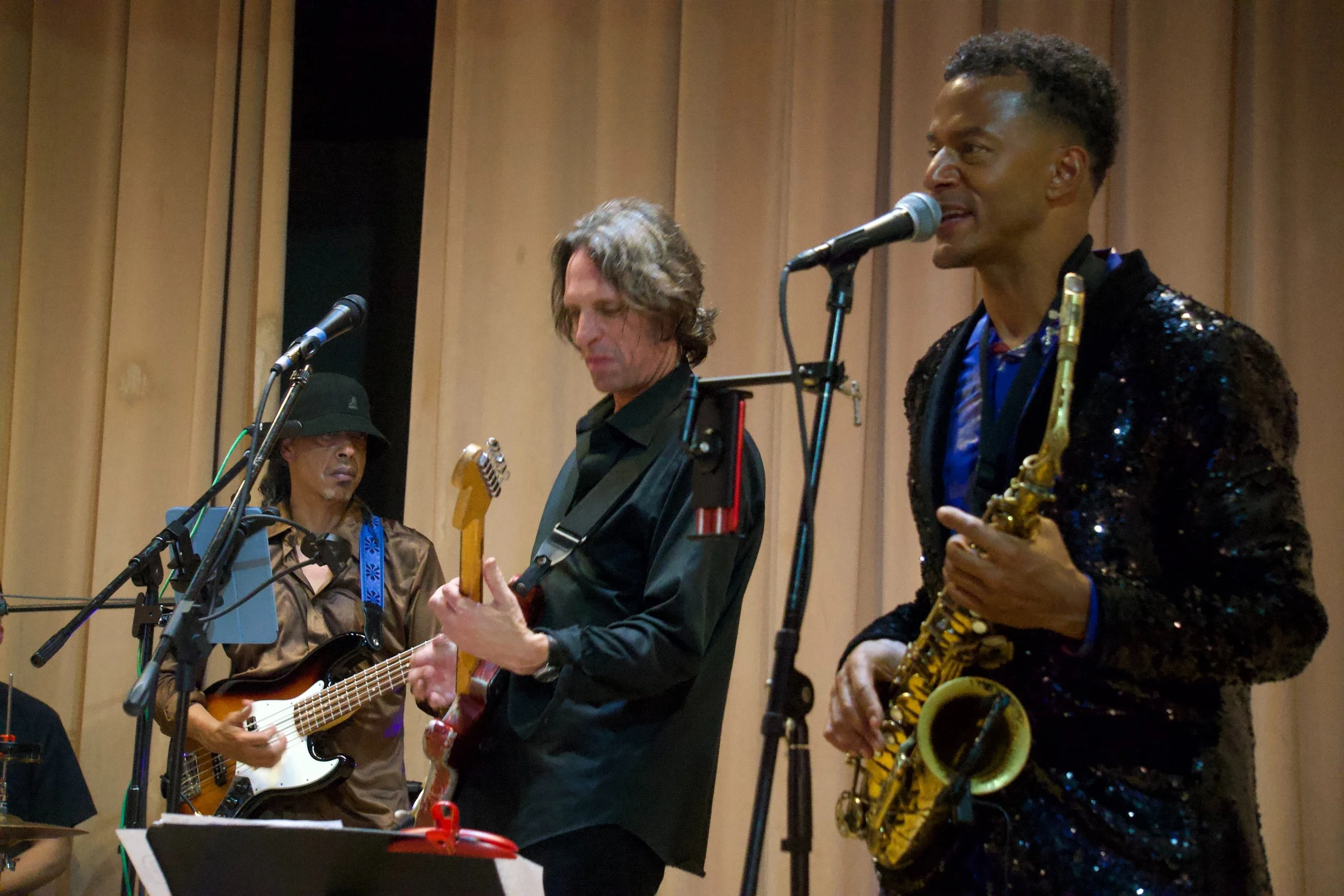 Live band performing on stage, with musicians playing guitar and saxophone under warm lighting, capturing the soulful, intimate energy of Shy Rockstar Studios.