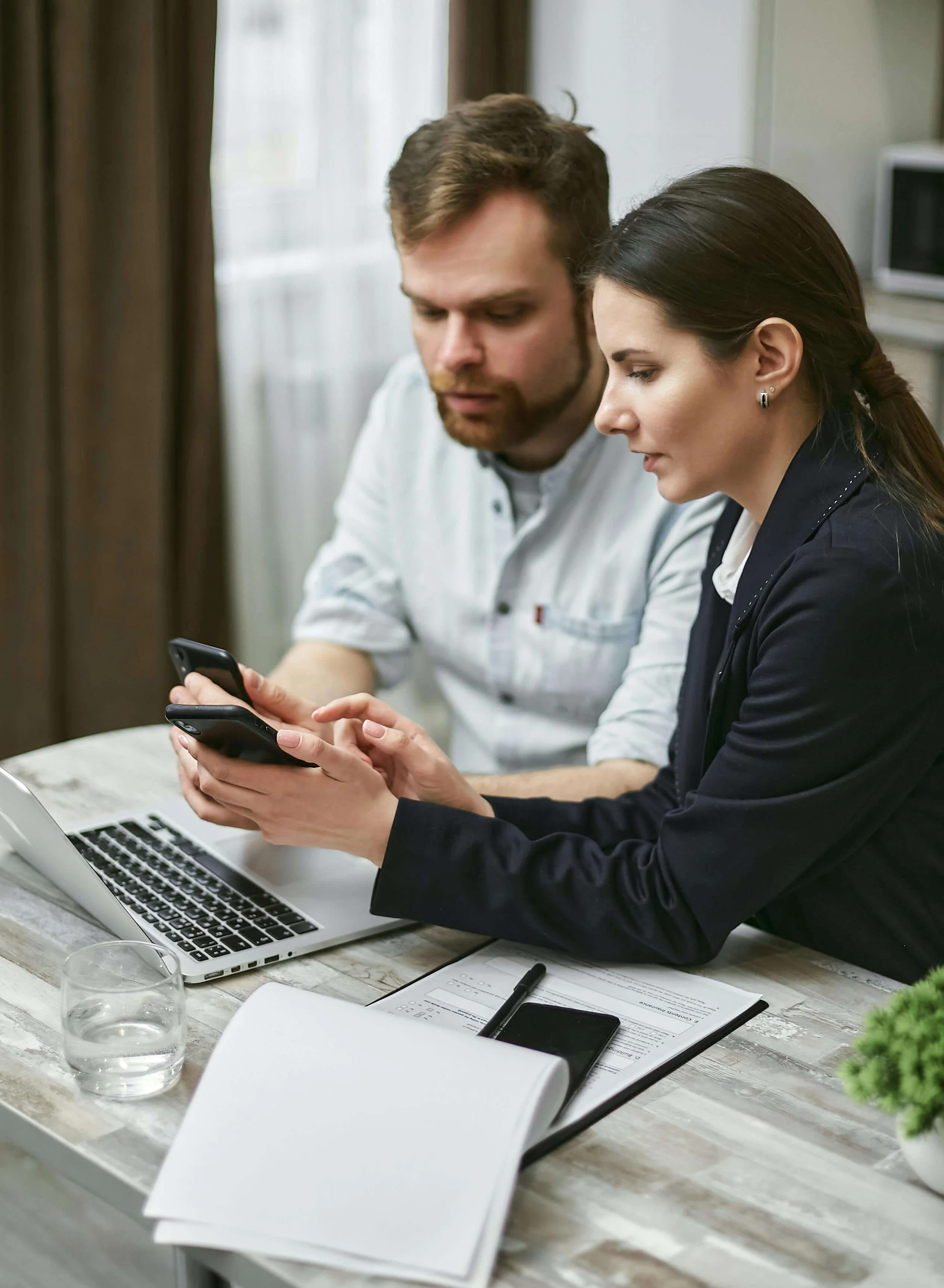 Two professionals reviewing documents on tablet at wooden table with laptop, notebook, and water glass in modern office. Understand why separate providers protect your case through expert substance abuse professional in Las Vegas, NV.