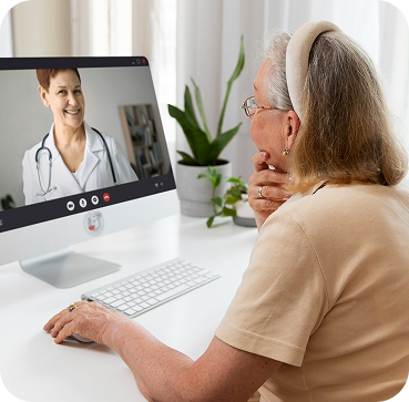 An elderly woman on a video call with a female doctor on a computer screen.