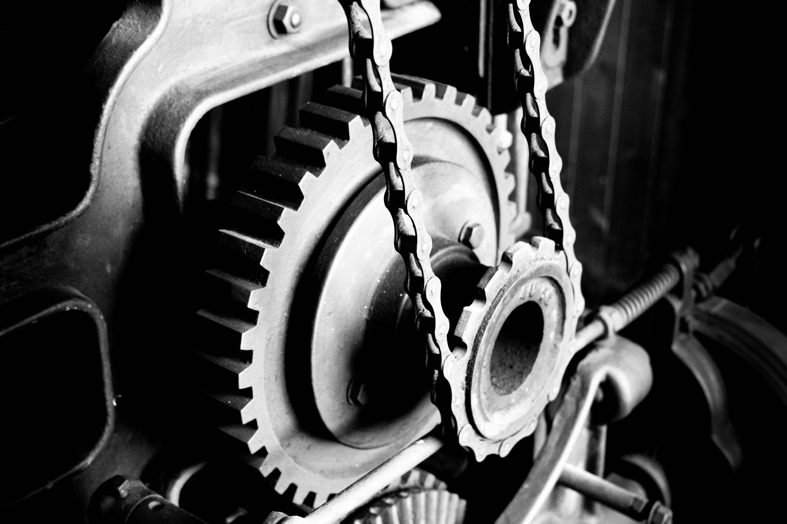 Close-up of metallic gears and chains in a mechanical system, black and white photography.
