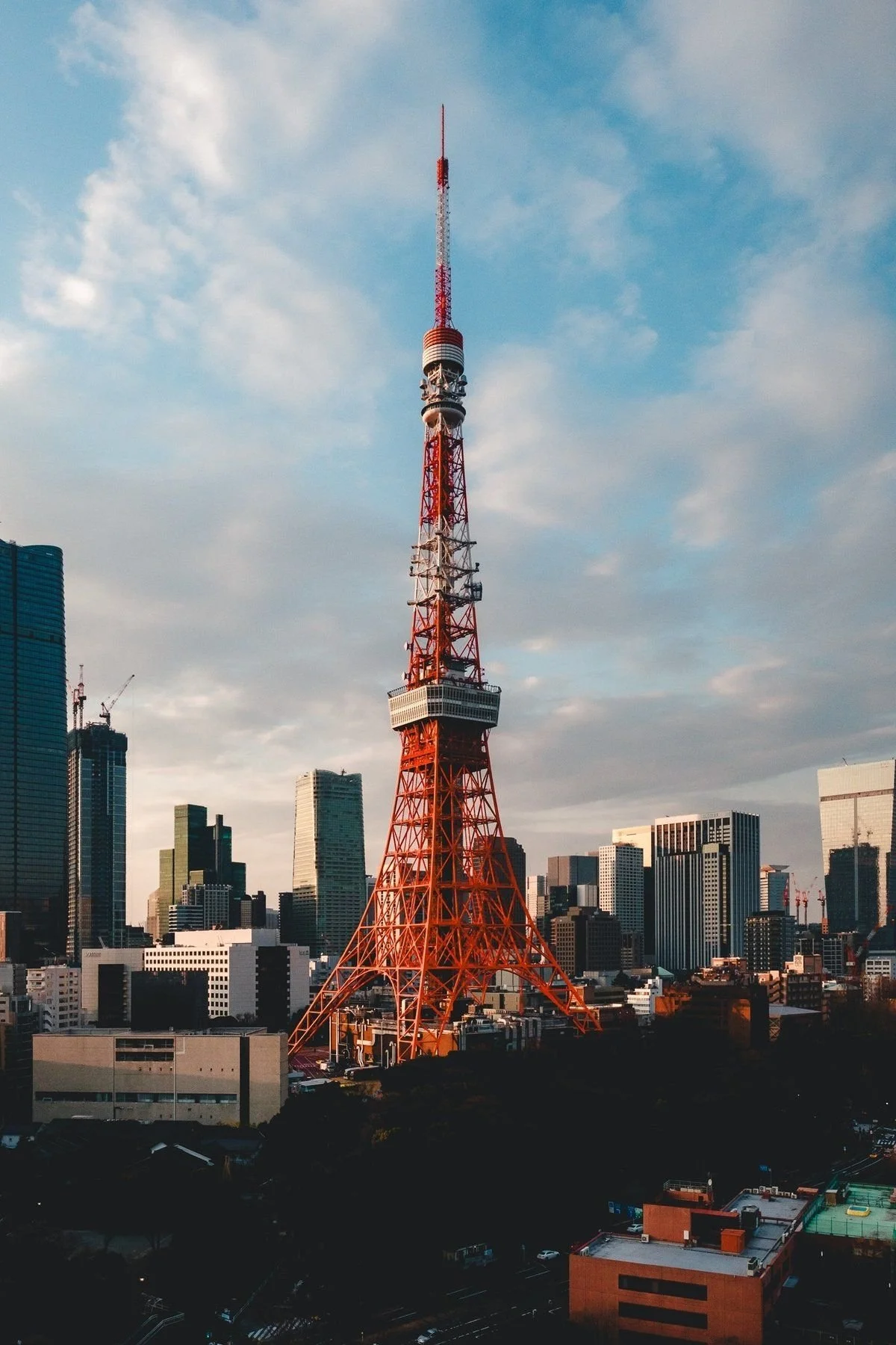 Imagen de la Torre de Tokio en Tokio, Japón, con edificios altos en el fondo y un cielo parcialmente nublado.