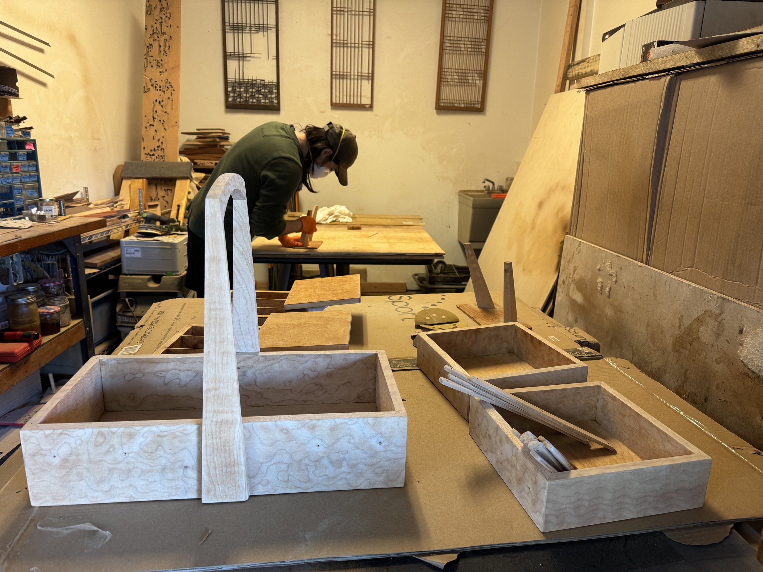 Person working on woodworking project in the Rescue Vintage workshop in Phinney neighborhood of Seattle with wooden boxes and tools around.
