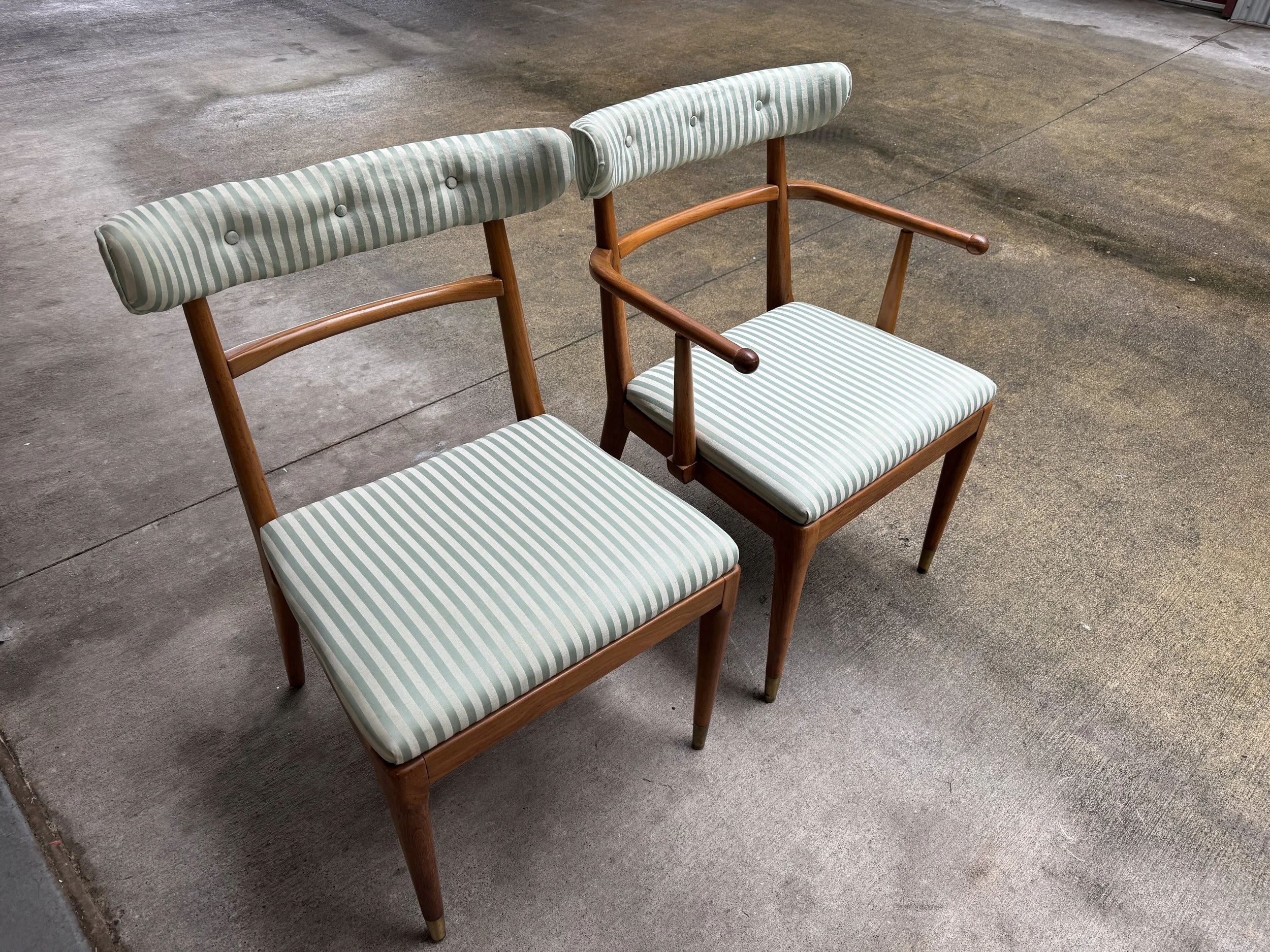 Two vintage wooden chairs with striped cushioned seats and backrests, placed on a concrete floor.