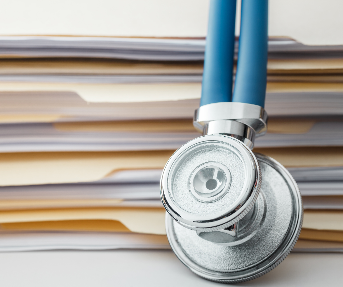 Stethoscope resting on a stack of medical files and documents