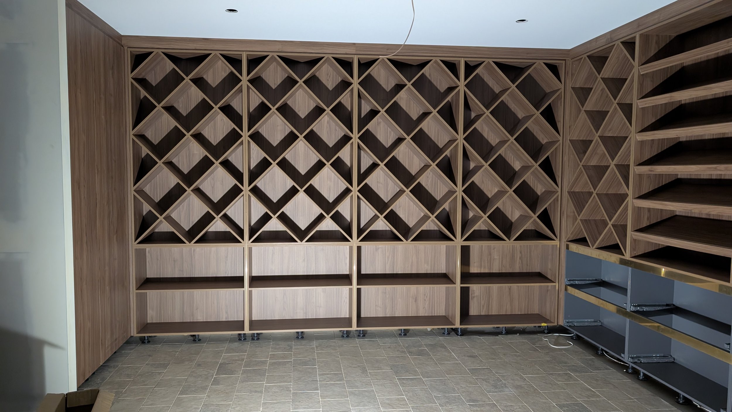 Wooden wine racks and shelves in a bare room with tiled floor.