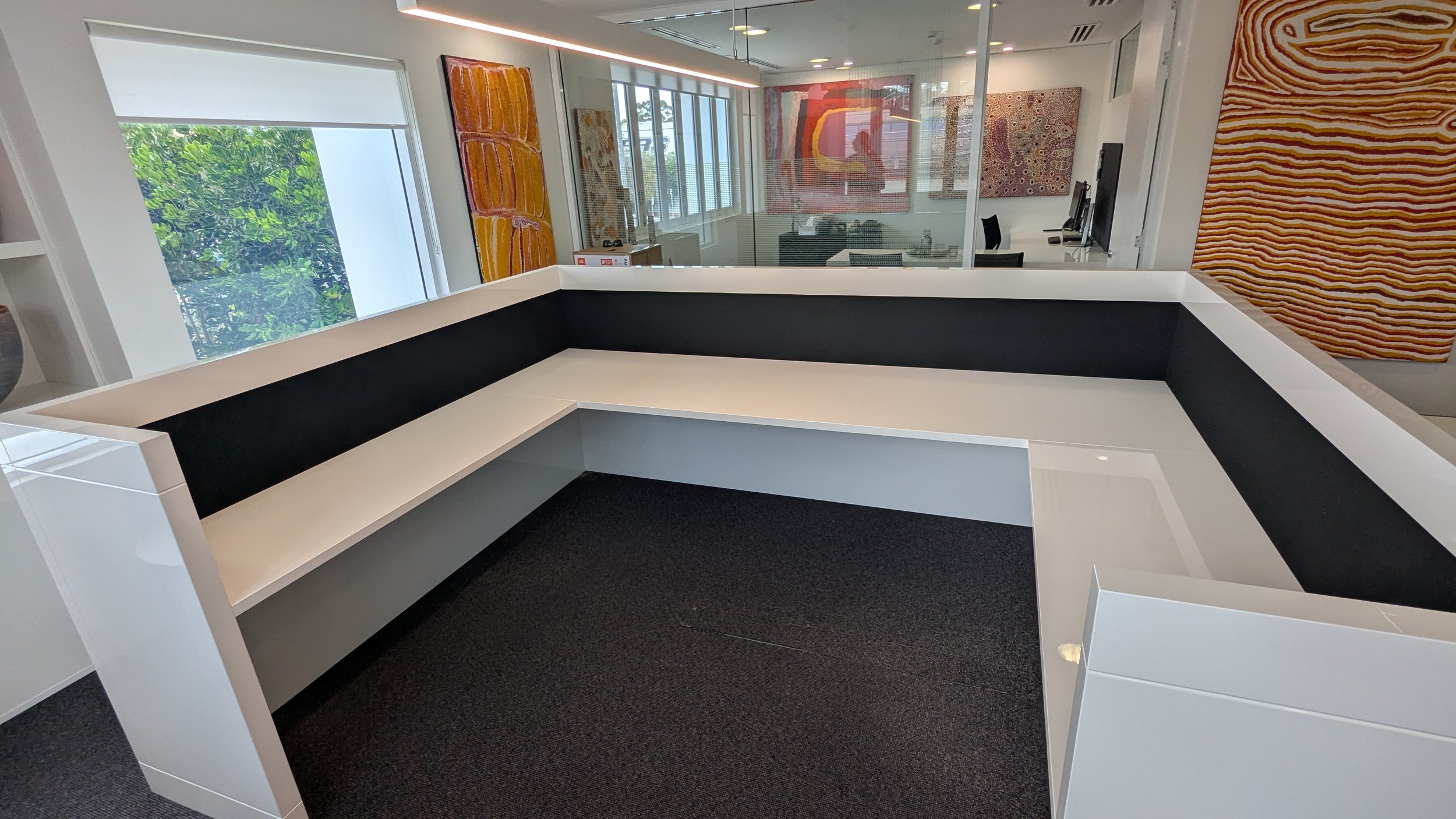 Empty modern office conference room with black and white built-in U-shaped seating and artwork on the walls.