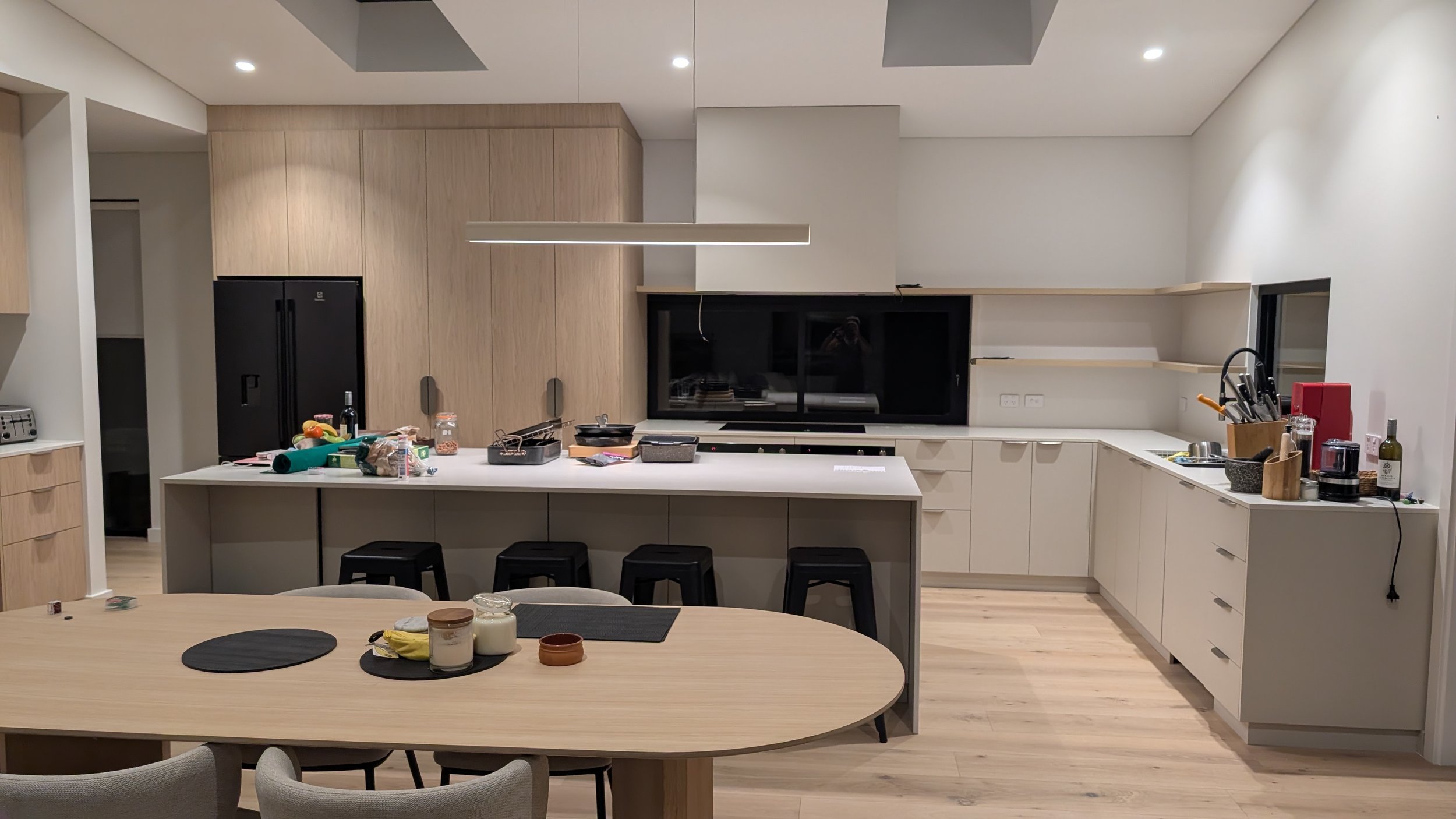Modern kitchen with white cabinets, black appliances, and a wooden dining table with chairs