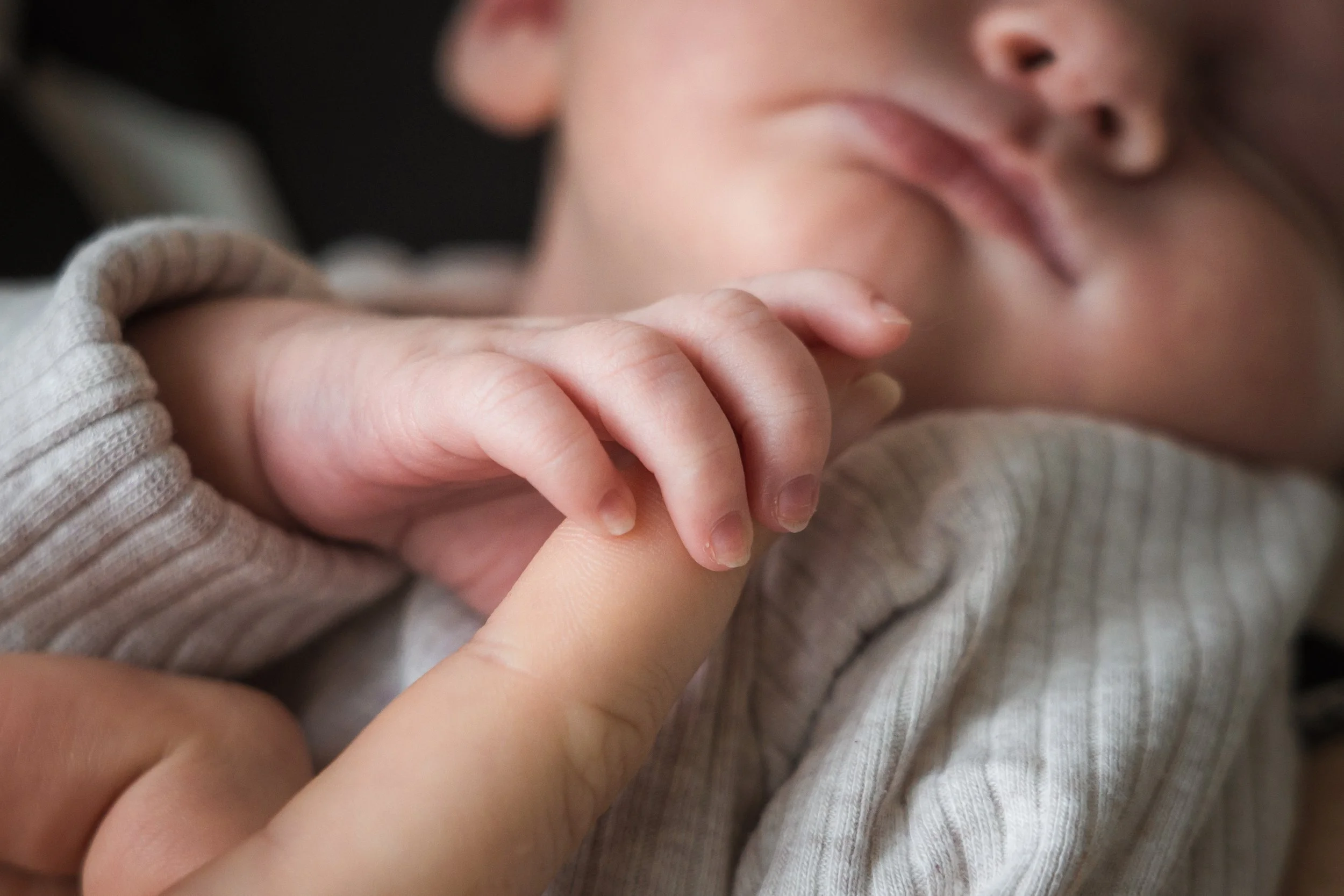 Close-up van een baby die een volwassen vinger vasthoudt.