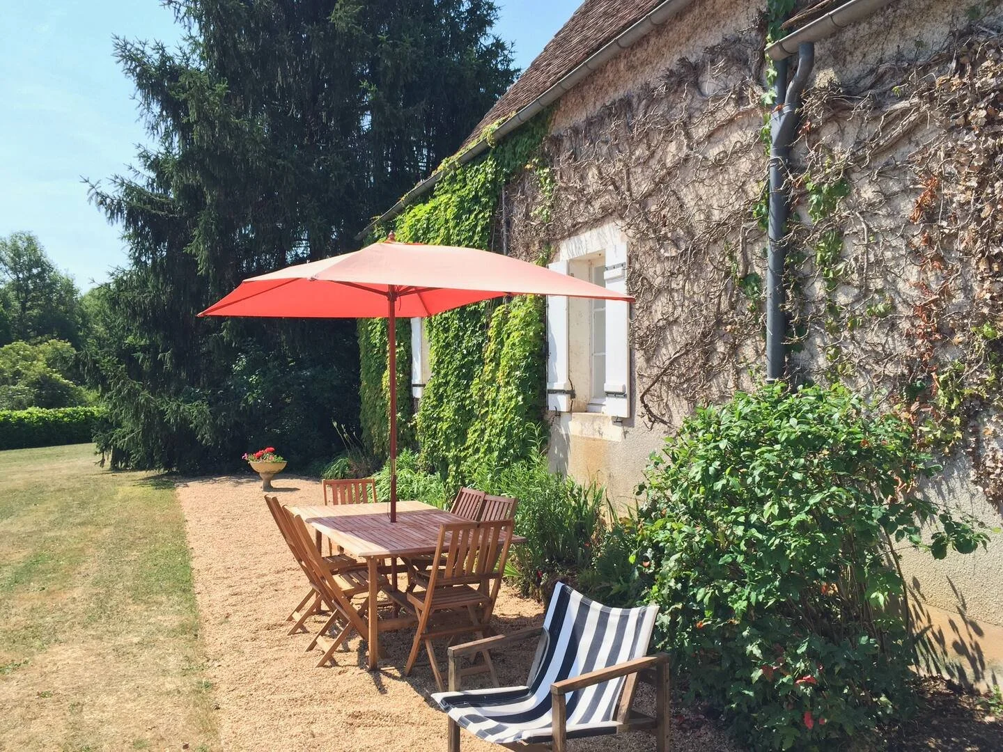 Outdoor patio with wooden table, chairs, and a pink umbrella at Tabary Farmhouse in the Dordogne