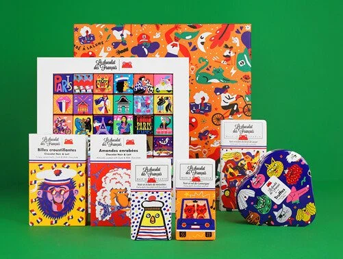 A collection of colorful illustrated chocolate boxes and packaging, featuring playful animal and fantasy theme designs, displayed against a green background.