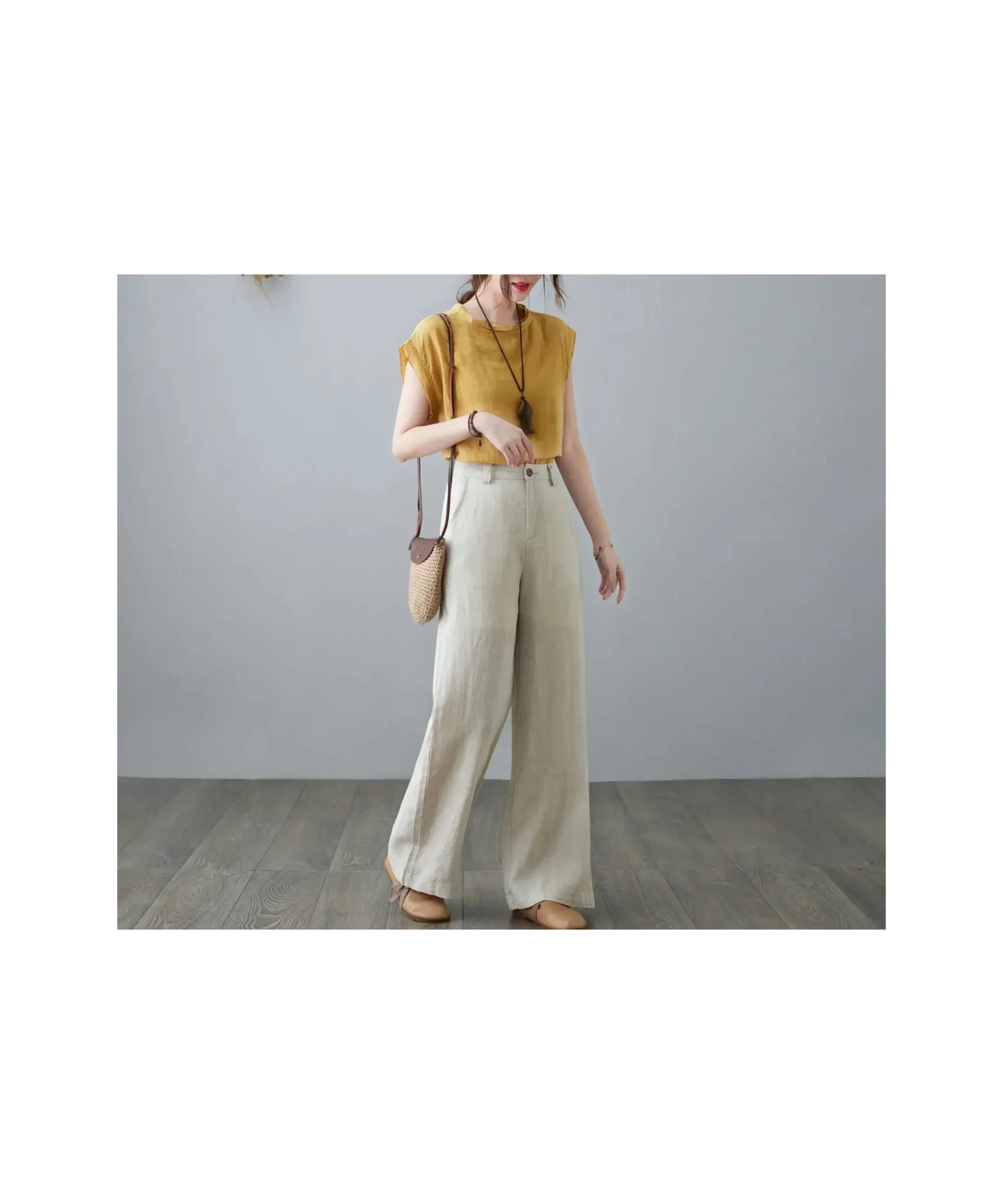 Minimal capsule wardrobe outfit featuring a mustard yellow sleeveless top paired with high-waisted wide-leg linen pants, styled with a small woven crossbody bag and neutral flats for an effortless, relaxed everyday look.