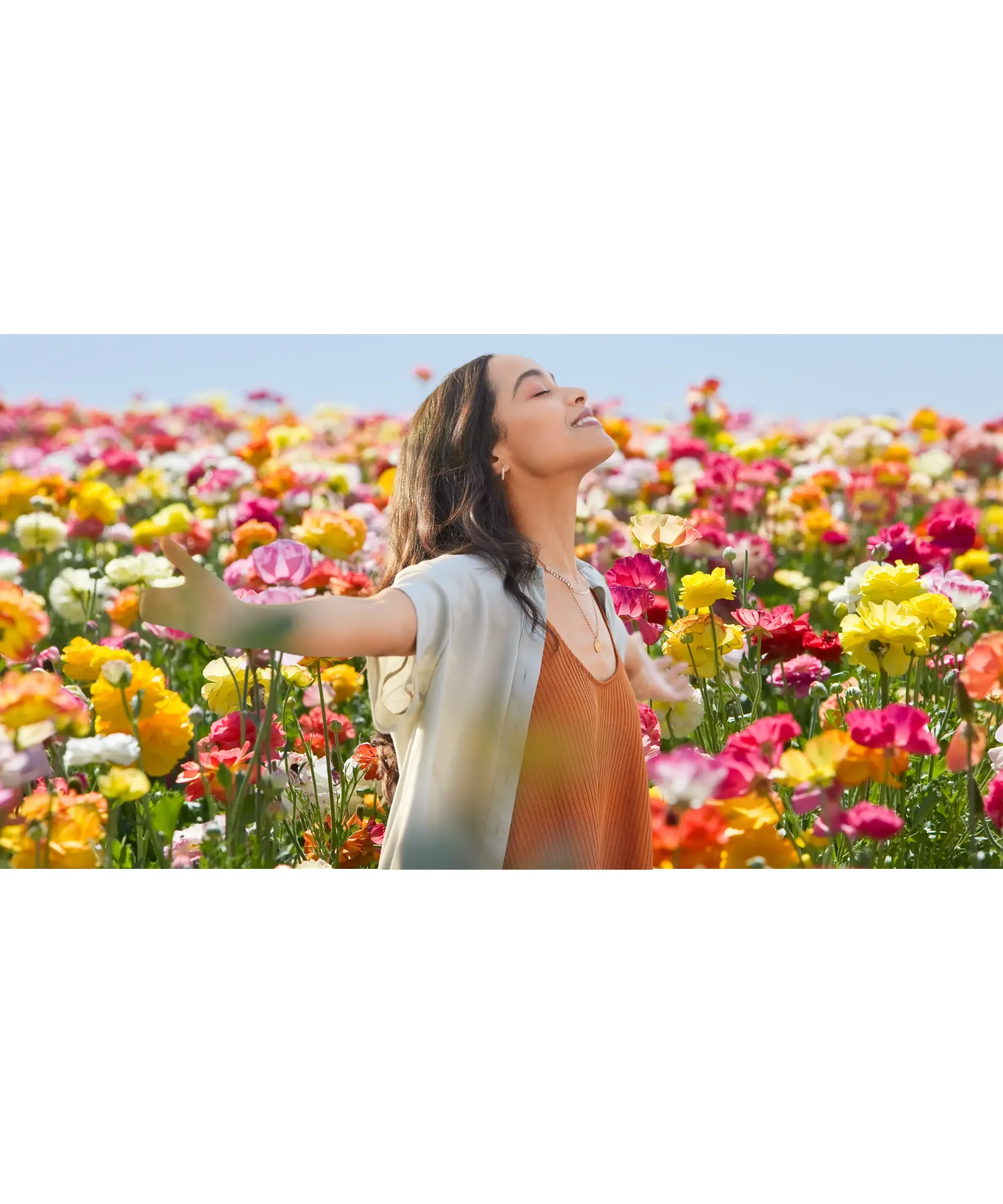 woman in a field of flowers with her arms wide open in gratitude
