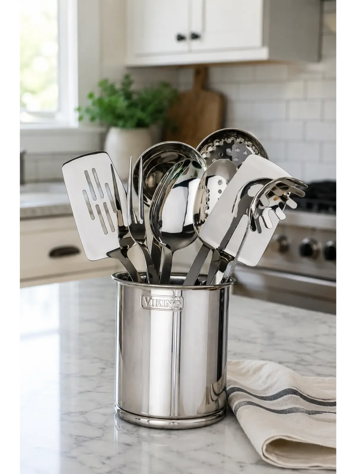 Modern stainless steel kitchen utensils displayed in a sleek countertop holder in a bright, clean kitchen.