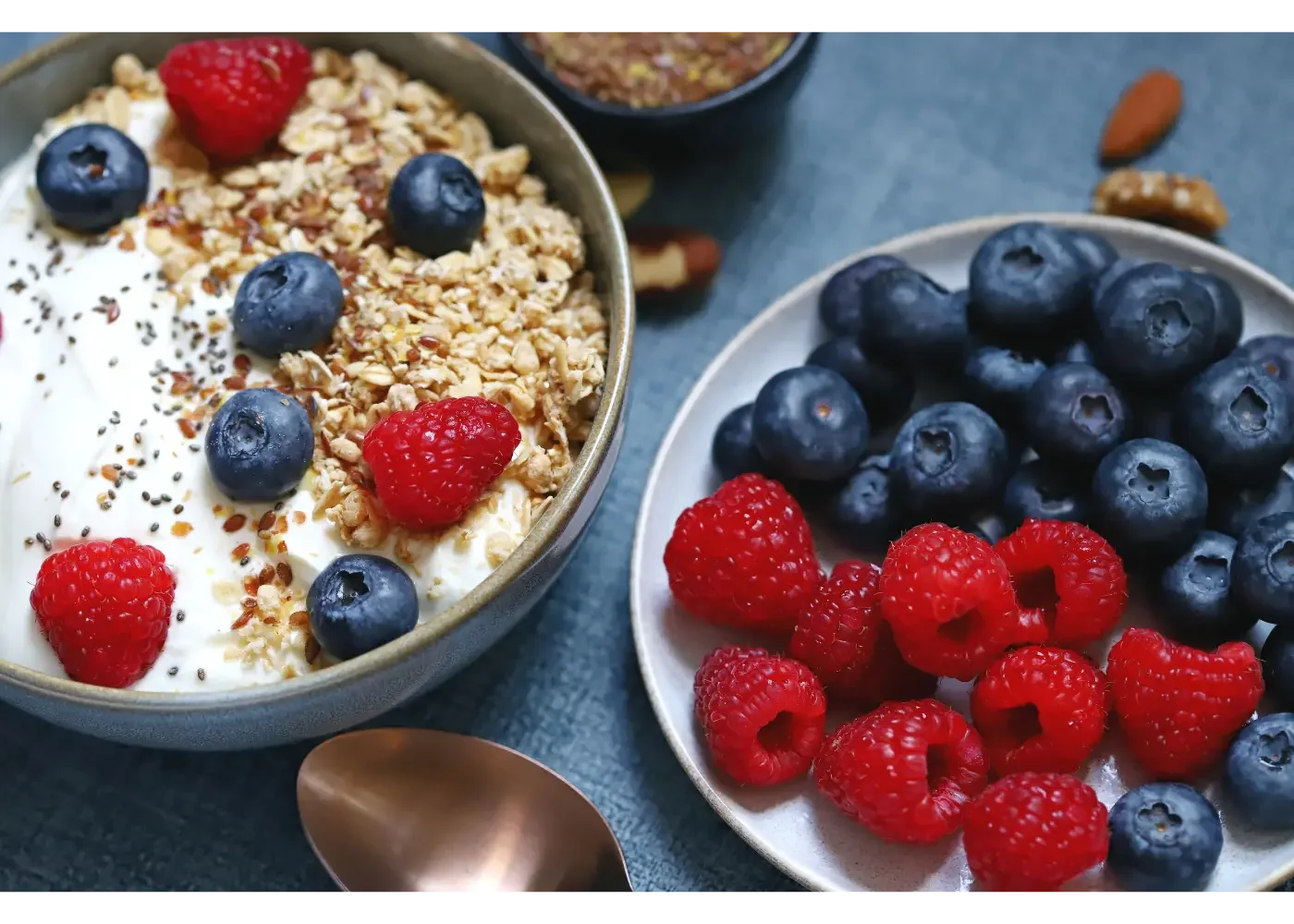 one bowl of yogurt with berries, and another bowl of berries on the side