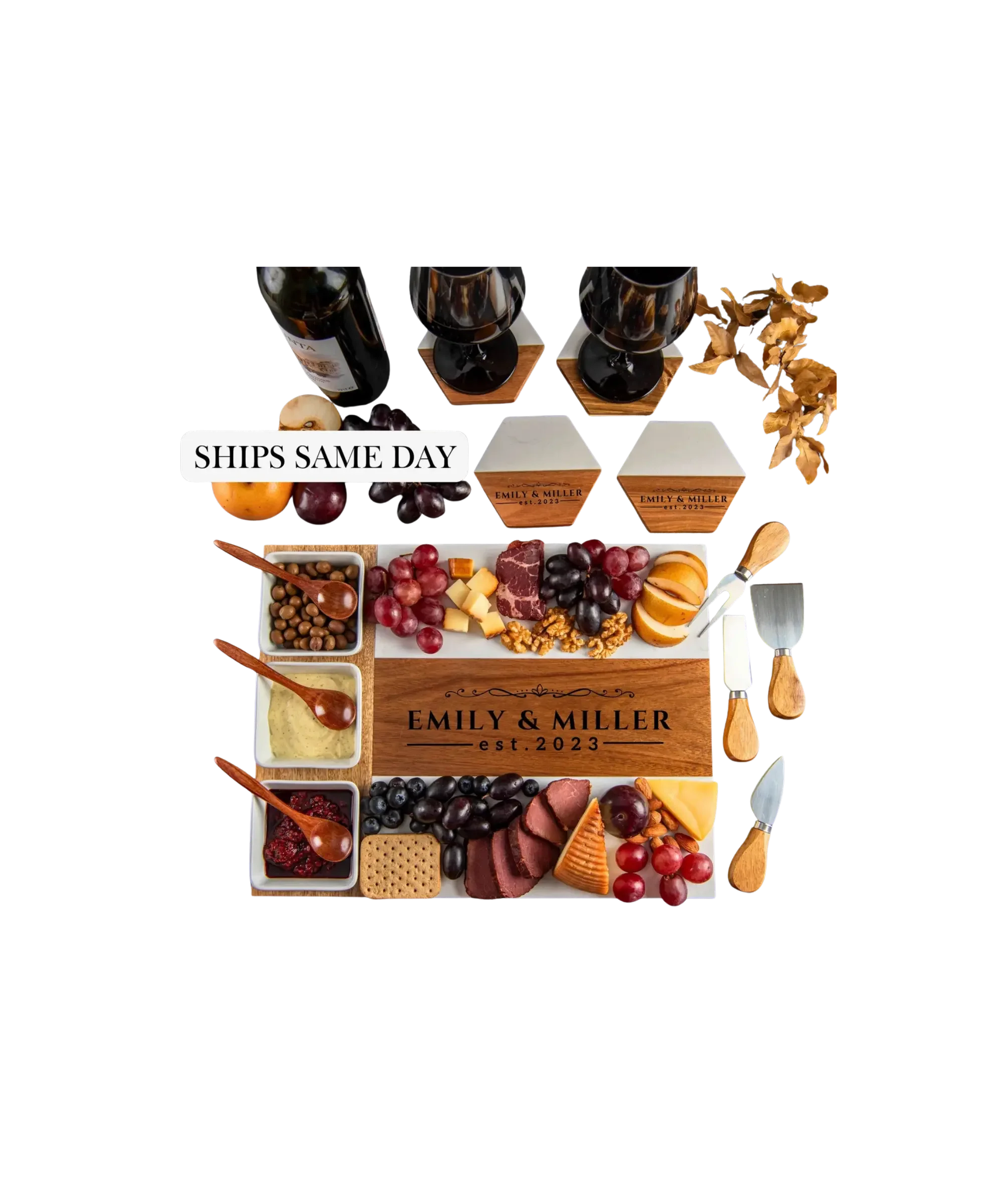 Personalized charcuterie board gift set engraved with names and date, wooden cheese board with wine glasses, cheeses, grapes, and serving utensils.