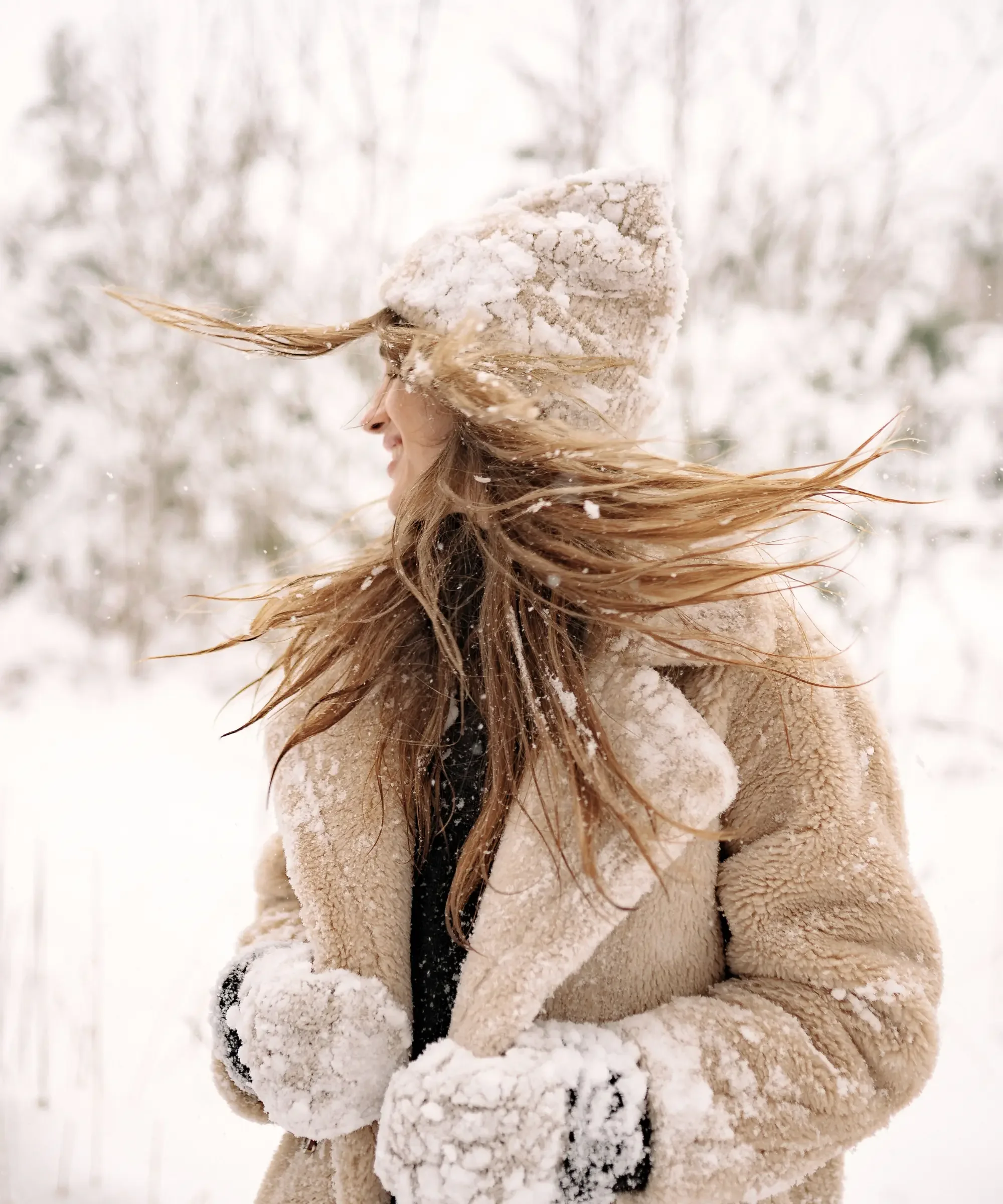 Woman standing outdoors in a snowy North Dakota winter, wearing a warm coat and hat as strong wind blows snow through her hair
