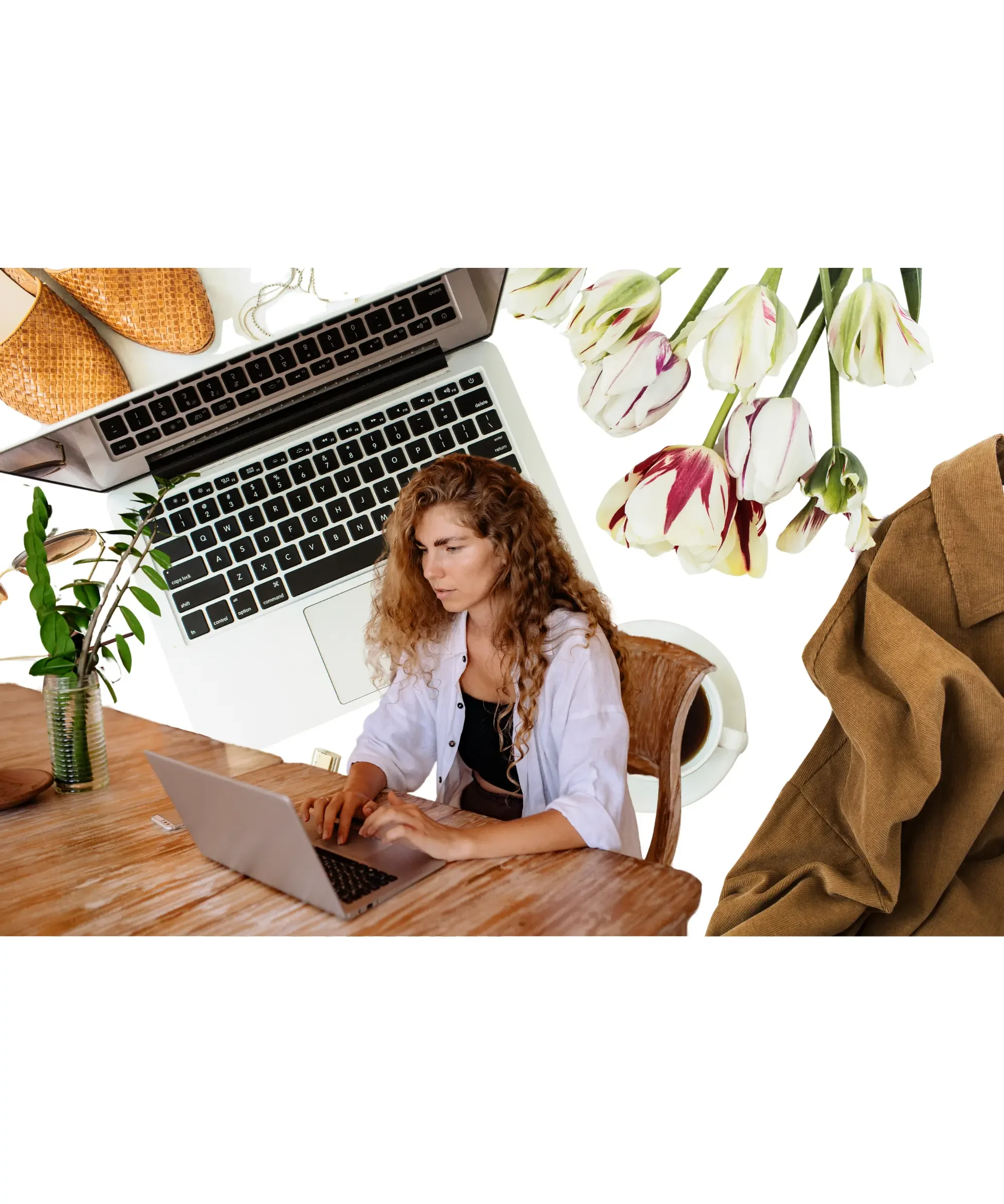 Woman working on laptop at wooden desk with coffee, flowers, and workspace items in bright home office setting