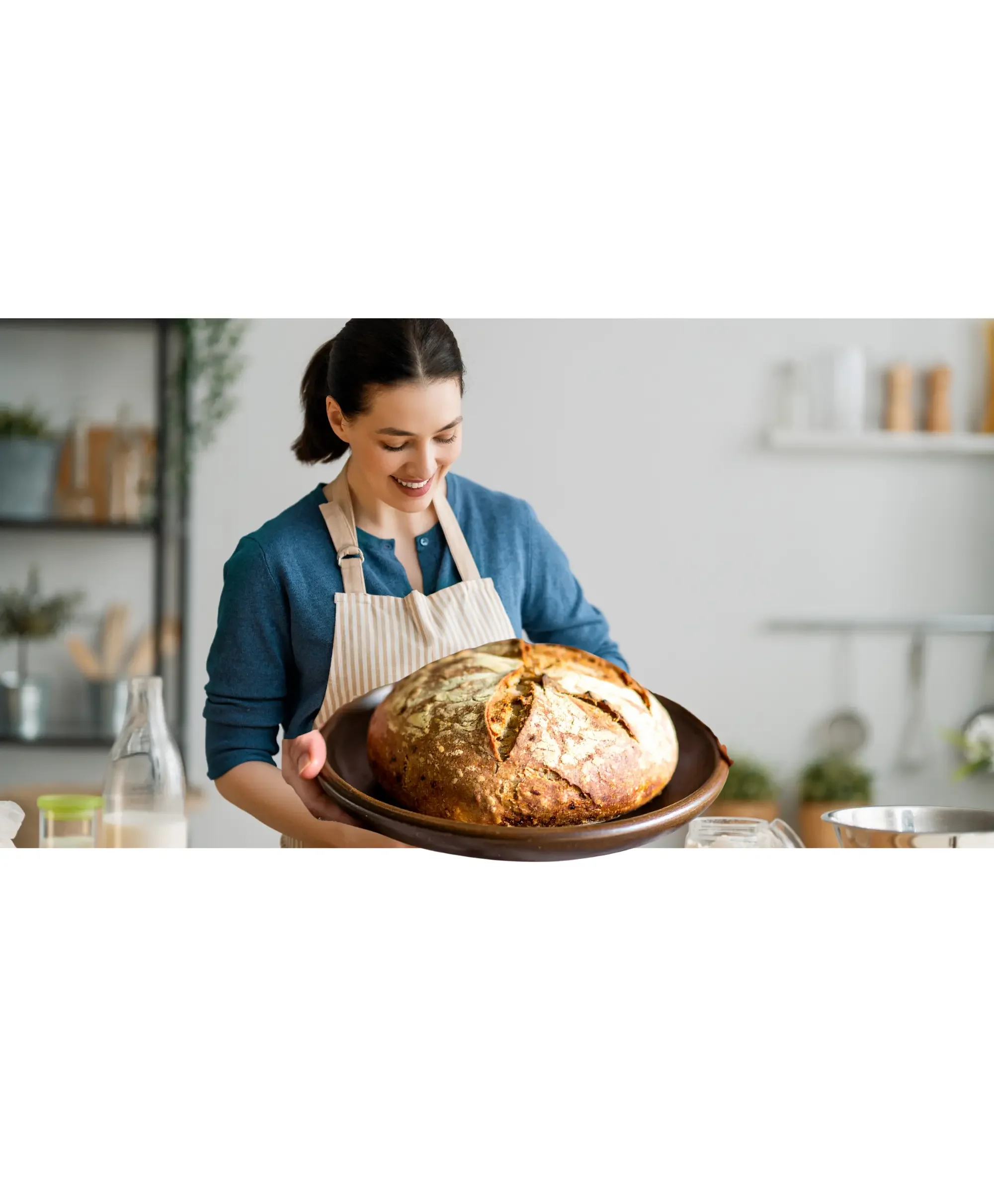 woman baking bread at home and holding a big loaf of bread