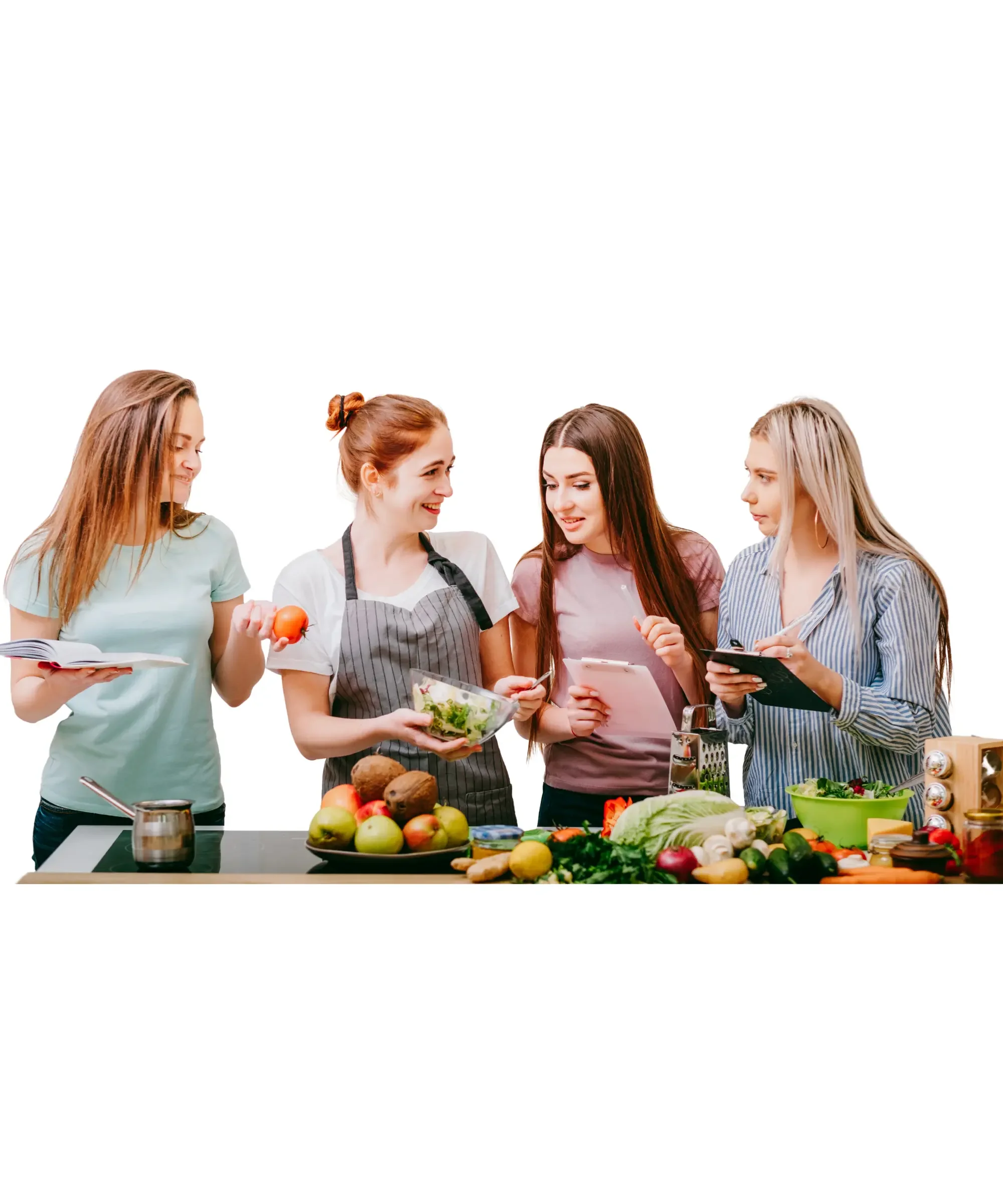 Four women standing together in a kitchen preparing fresh food, holding vegetables, a salad bowl, and a recipe notebook, with a counter full of fruits and vegetables in front of them.