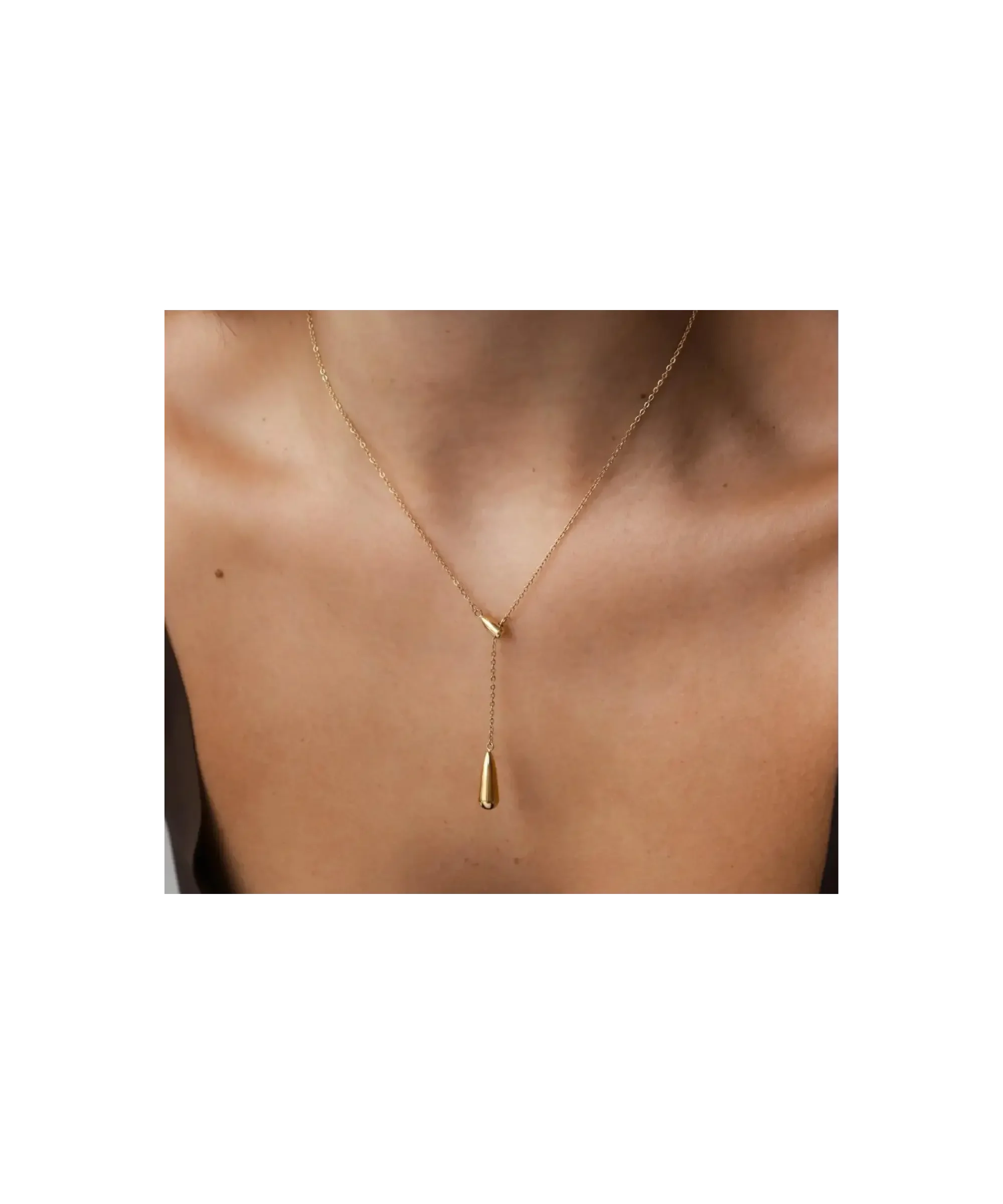Minimal gold drop necklace with delicate chain and vertical pendant, styled on bare skin for an elegant, timeless capsule wardrobe look.
