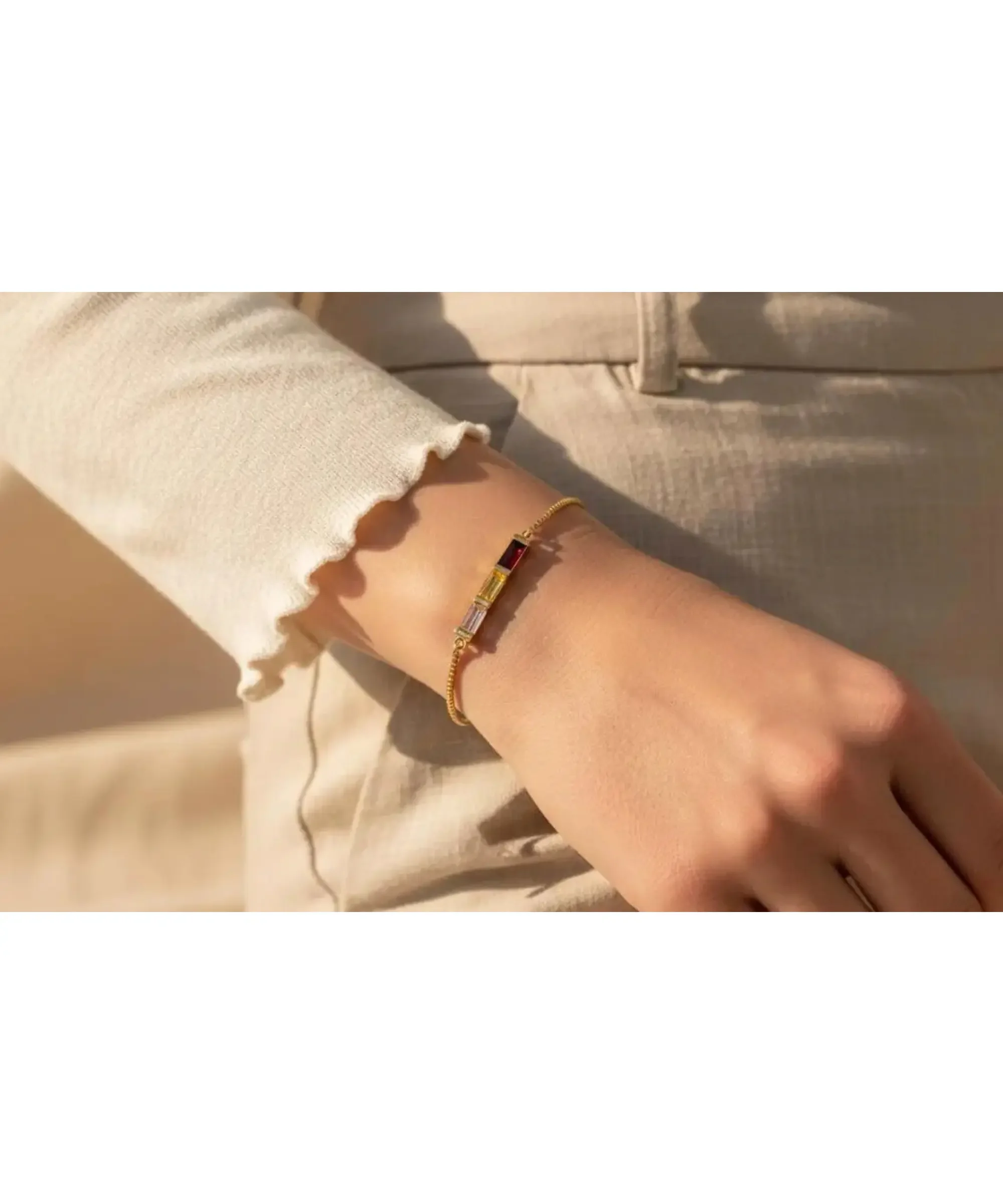 Custom baguette birthstone bracelet in gold worn on wrist.