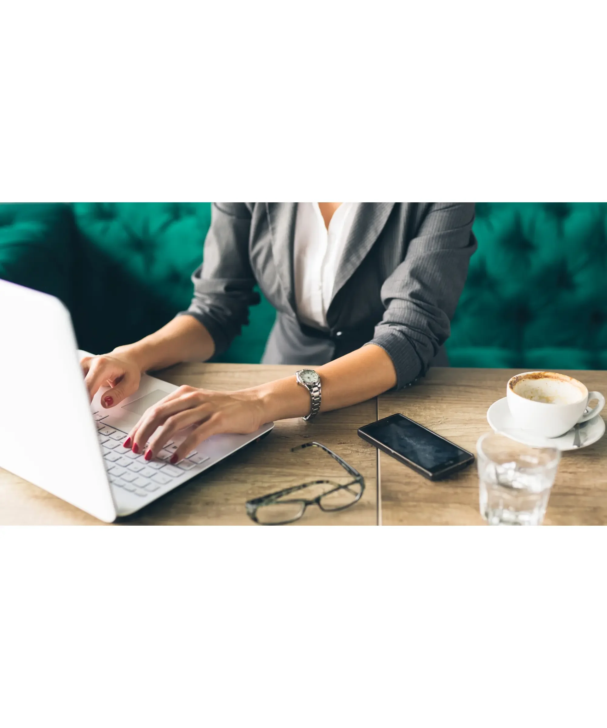 Woman working on a laptop with notes and coffee, representing research and tracking health or lifestyle changes.