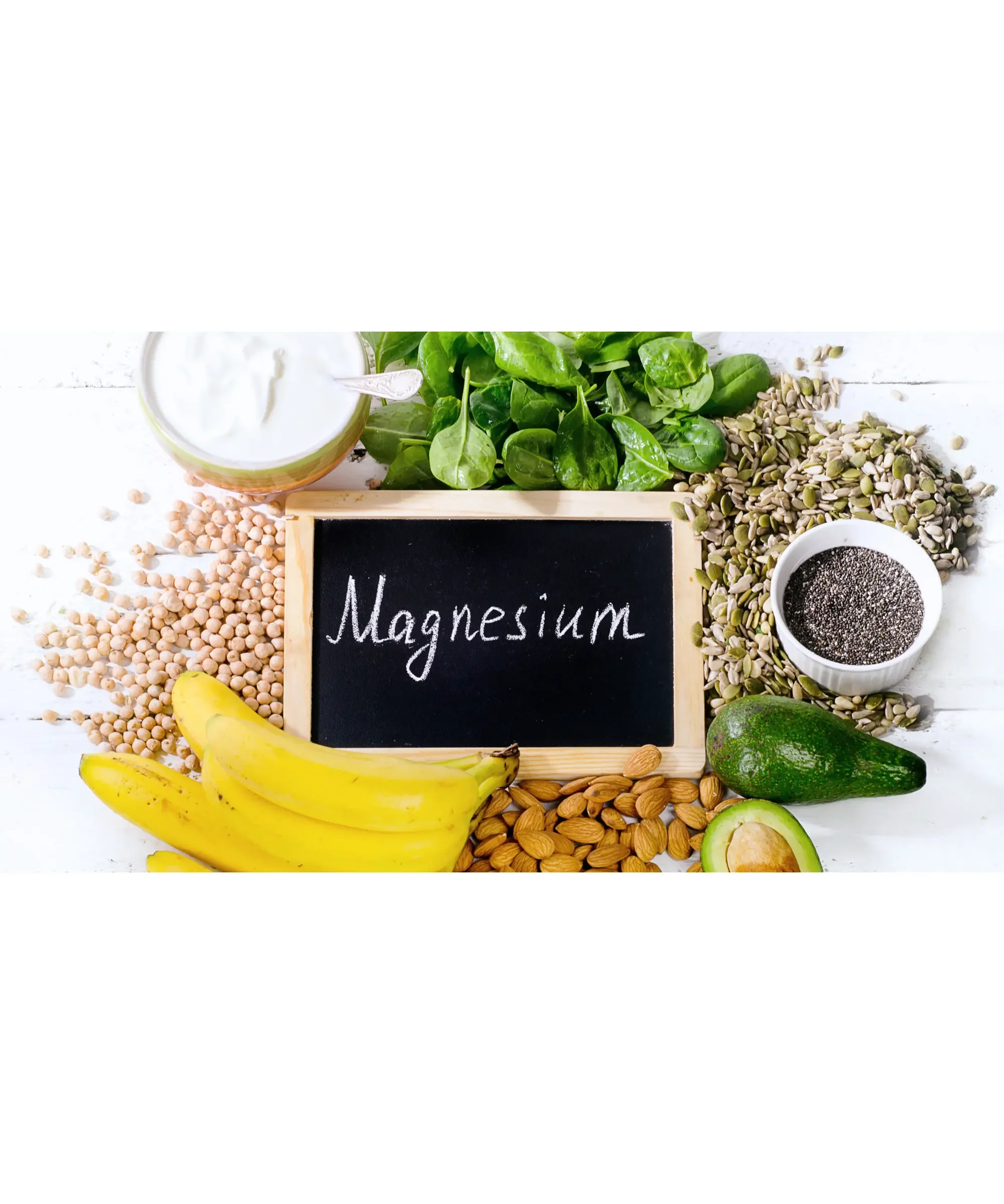 “Assorted magnesium-rich foods including bananas, spinach, nuts, seeds, avocado, and yogurt arranged around a small chalkboard with the word ‘Magnesium’ written on it.”