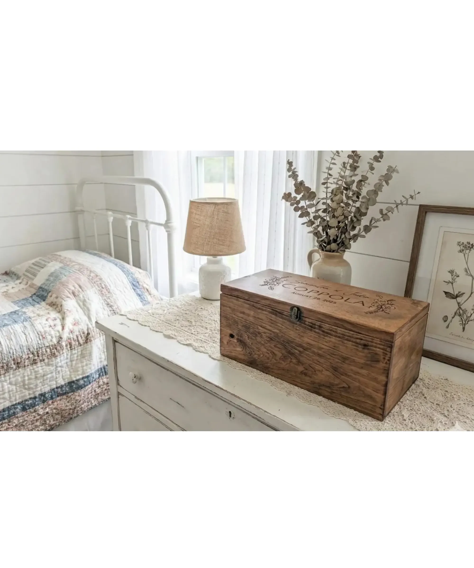 Personalized wooden keepsake box with engraved name placed on a white farmhouse dresser beside a lamp and dried eucalyptus, creating a cozy bedroom setting.