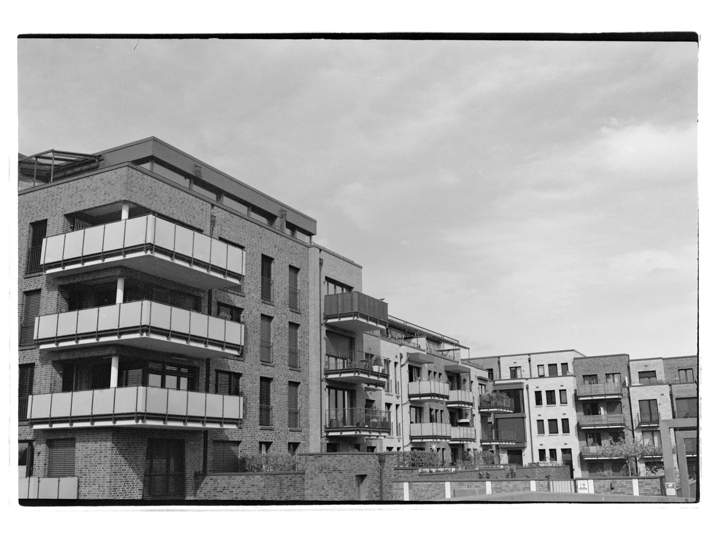 Mehrstöckige moderne Apartmentgebäude mit Balkonen und Brücken in Vechta, Ansicht in Schwarz-Weiß.