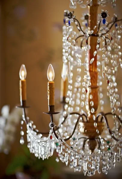 Close-up of an elegant chandelier with lit candle-style bulbs and hanging crystal beads.