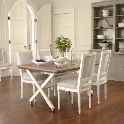 Dining room with wooden table and six white chairs, a built-in cabinet with dishes, and a potted plant