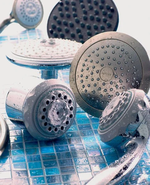 Multiple showerheads and shower fixtures on a tiled bathroom wall
