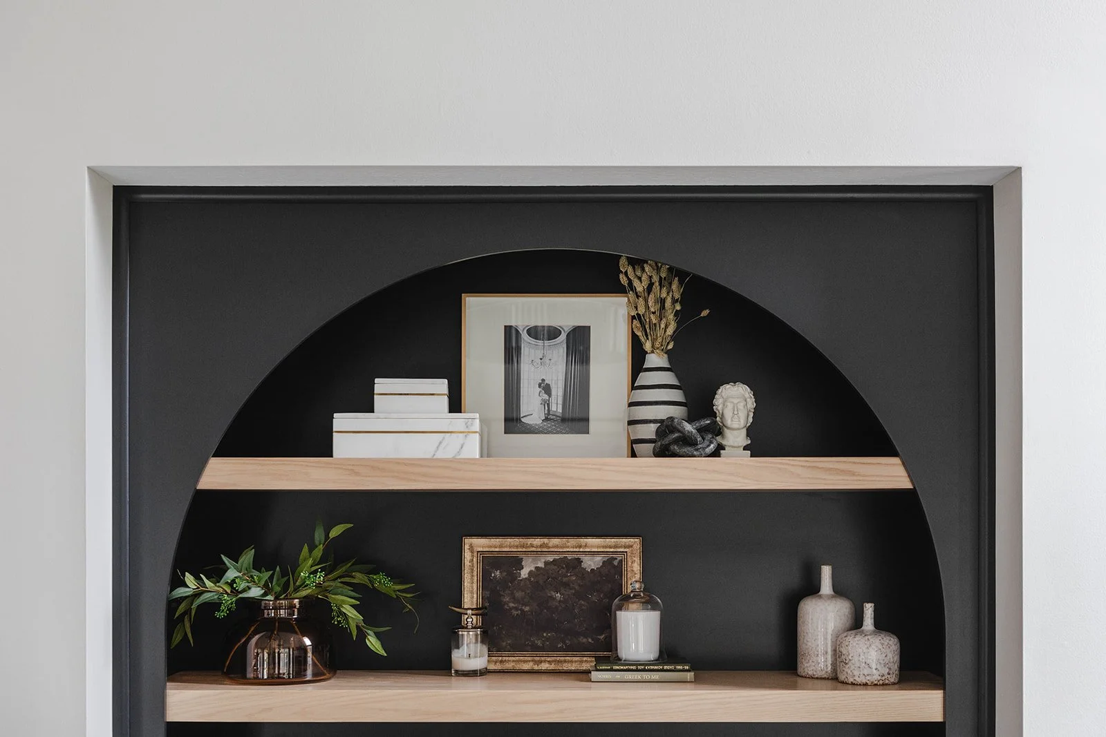 Decorative shelves with books, plants, artwork, vases, and sculptures in a modern interior