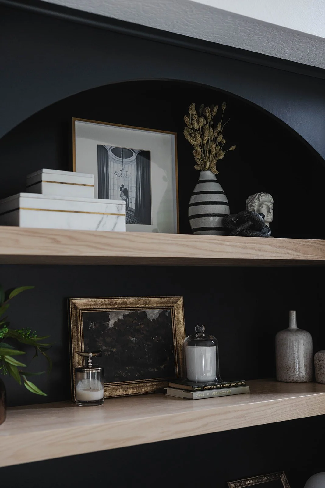Decorative shelves with framed photos, vases, candles, and art pieces against dark walls.
