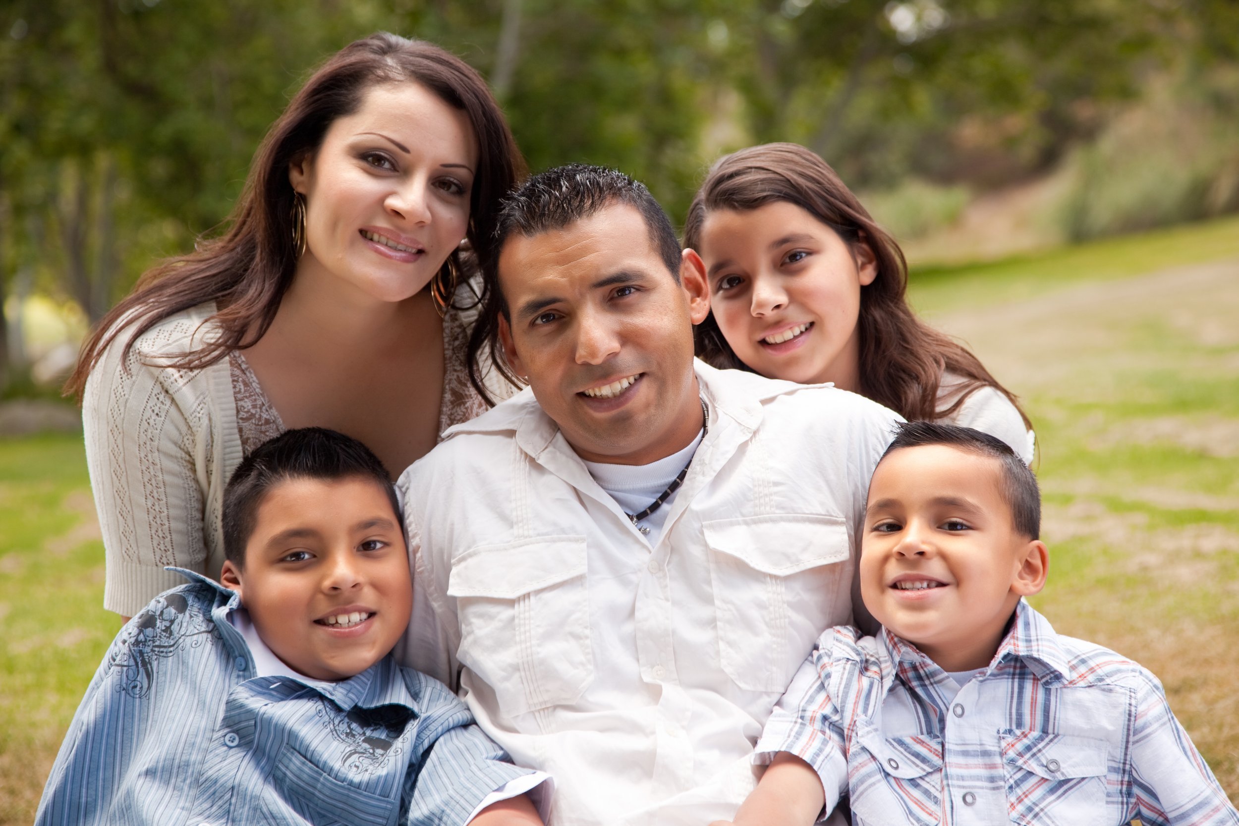 An image of an immigrant family of five smiling for the camera.