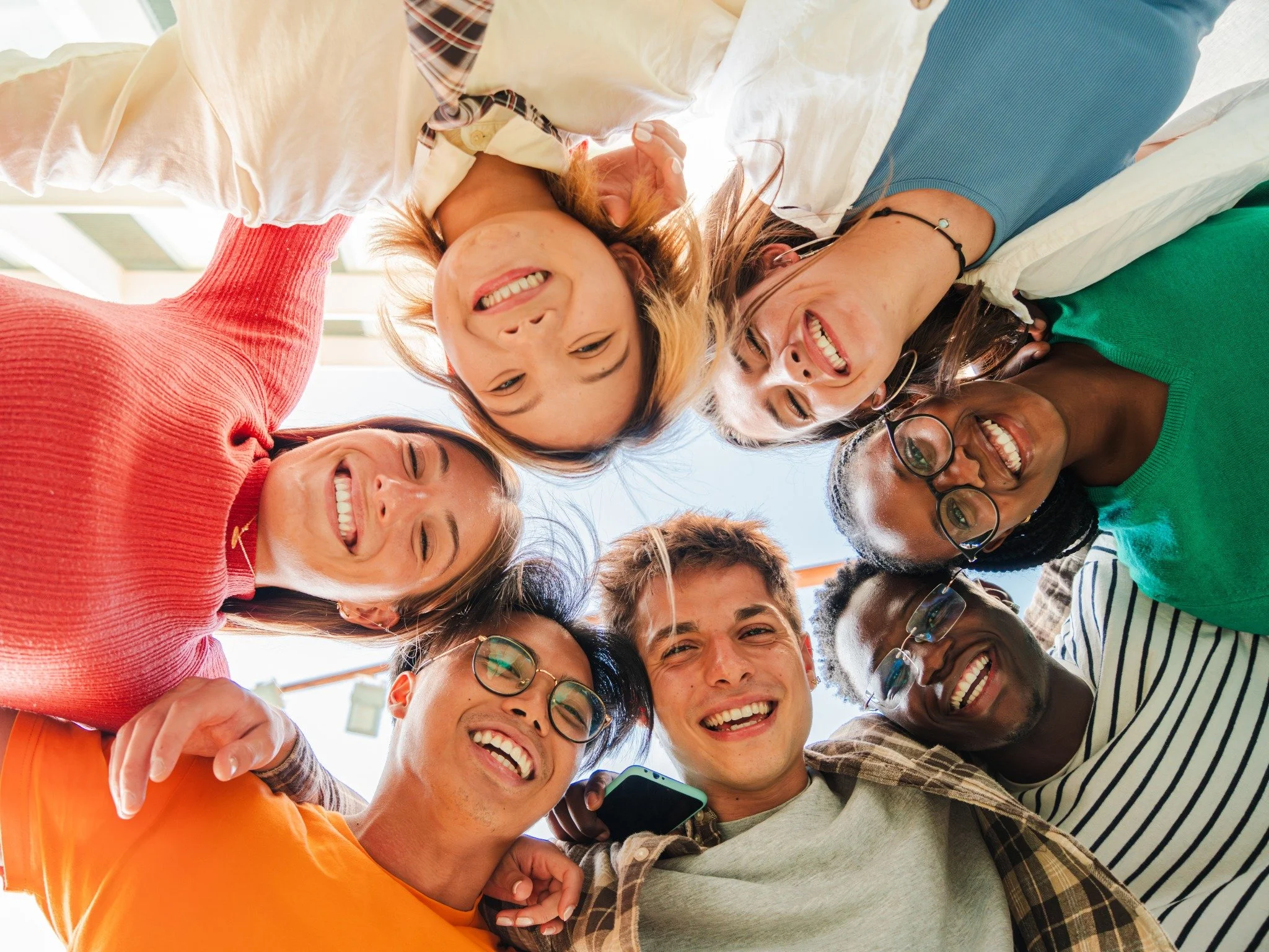 A group of smiling students gathered in a circle outdoors.