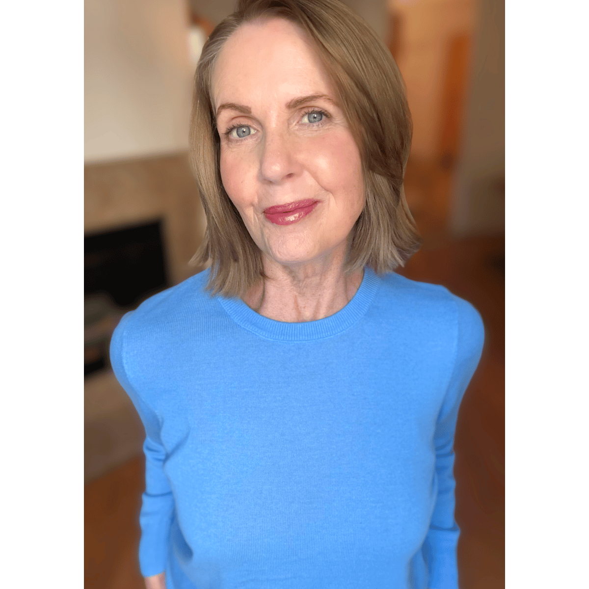 Lori Massicot in a bright blue sweater standing with her hands on hips smiling at the camera.