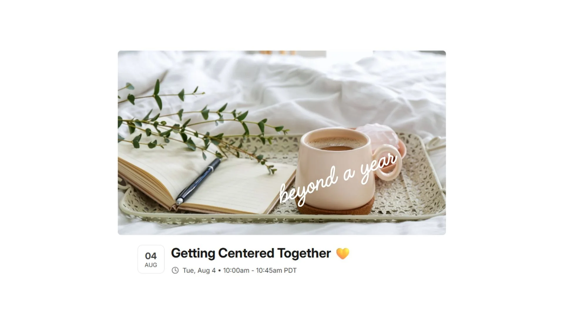 Image shows a coffee cup, open journal with a pen, on a tray with greenery sitting on a bed with white comforter.