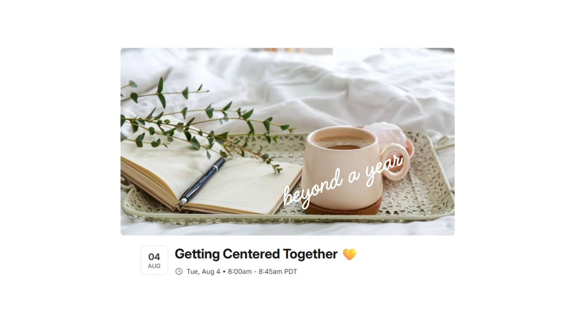 Image shows a coffee cup, open journal with a pen, on a tray with greenery sitting on a bed with white comforter.