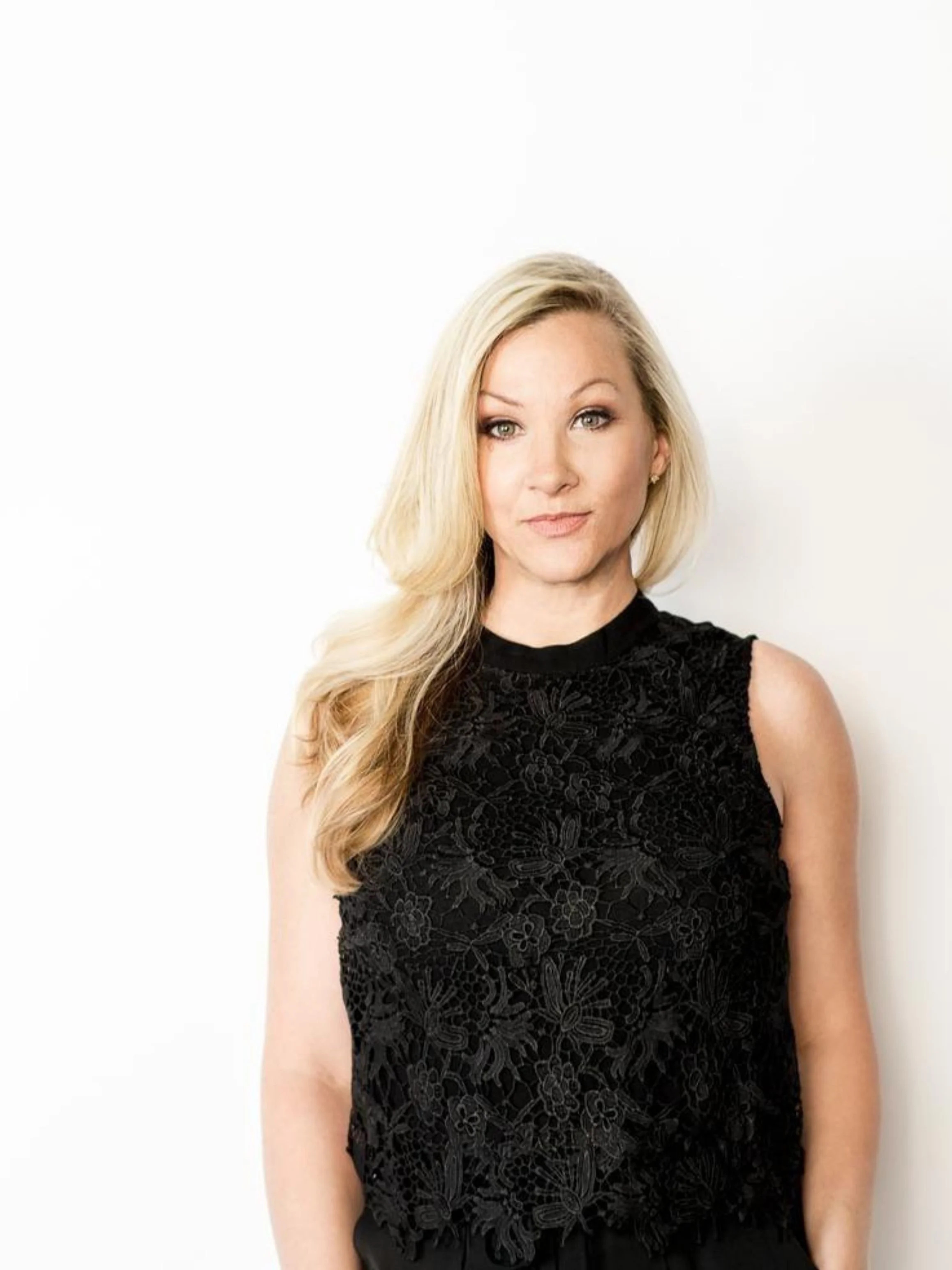 Angela Pugh portrait for To 50 and Beyond podcast episode about addiction recovery and 12 step programs, blonde woman in a black lace top against a white background.