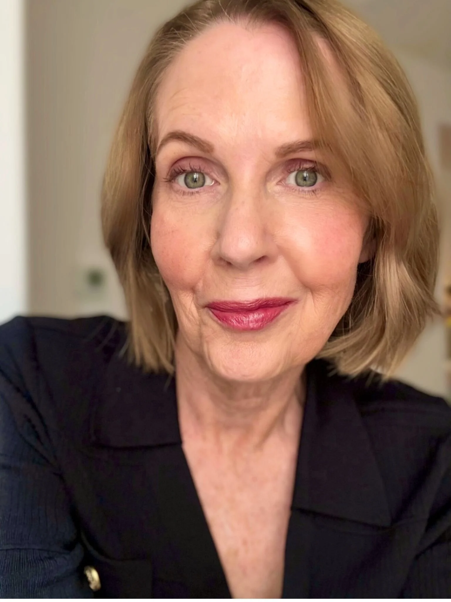 Lori Massicot wearing a black top with a gold button showing. Looking at the camera smiling.