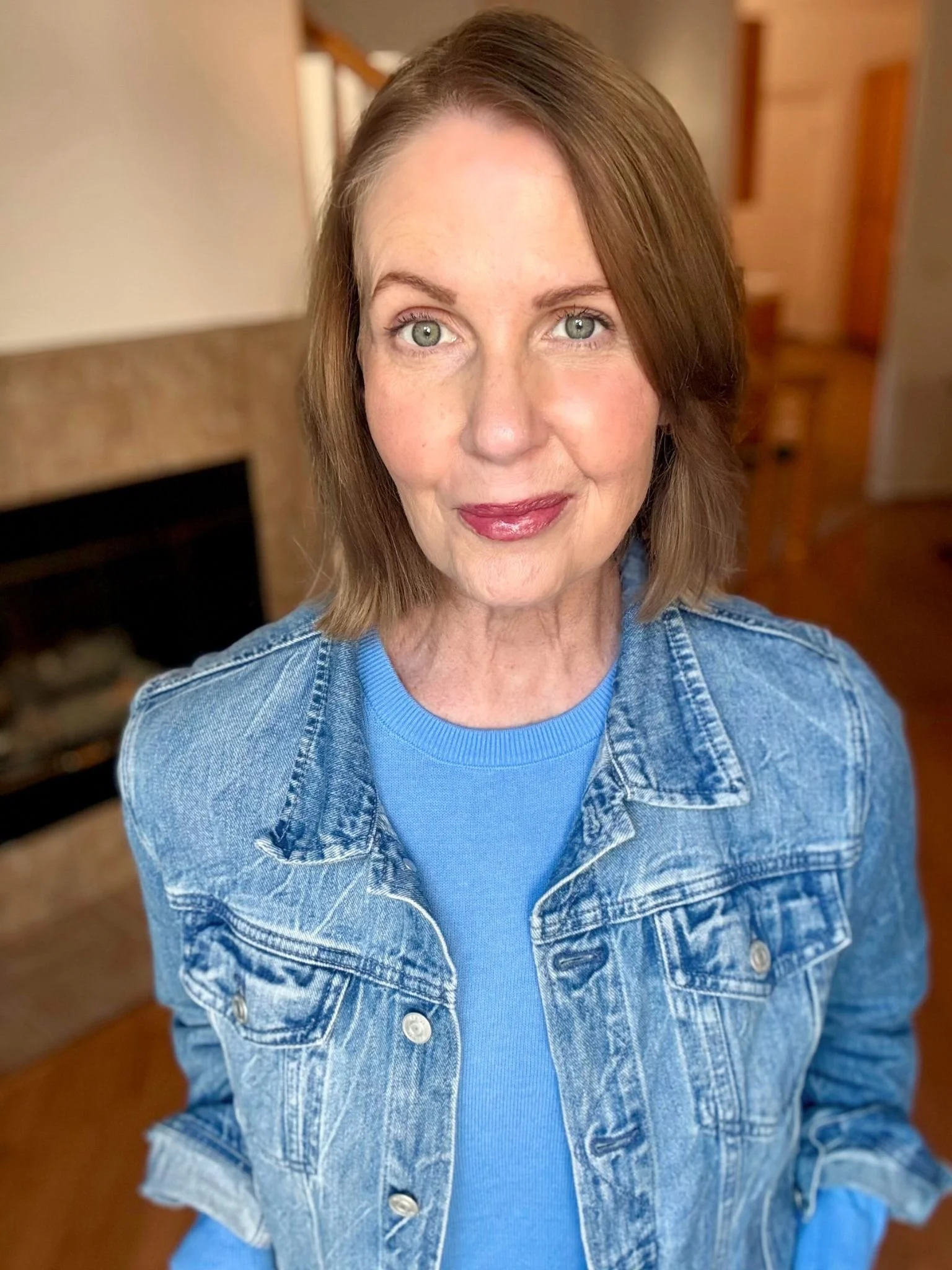 Lori Massicot wearing a blue jean jacket with a bright blue sweater looking at the camera smiliing.